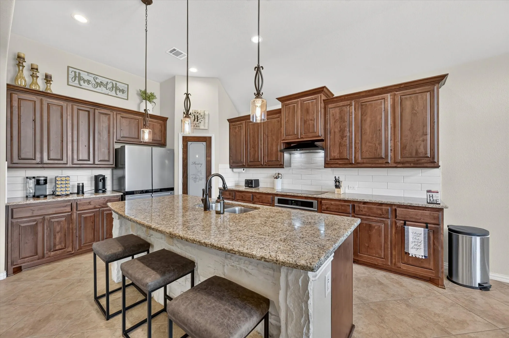 Kitchen featuring wood-finish cabinetry, granite countertops, and a subway tile backsplash