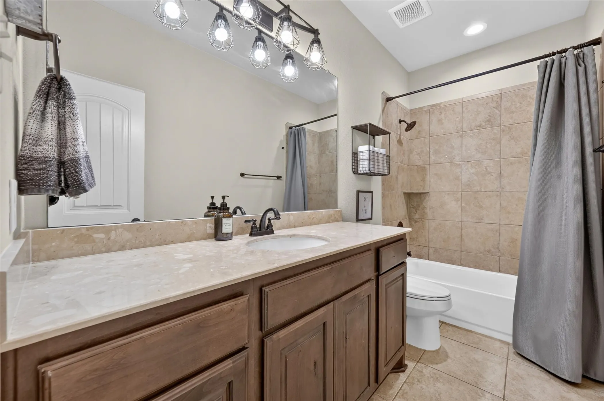 Wood-finish vanity with a stone countertop, undermount sink, and dark bronze faucet