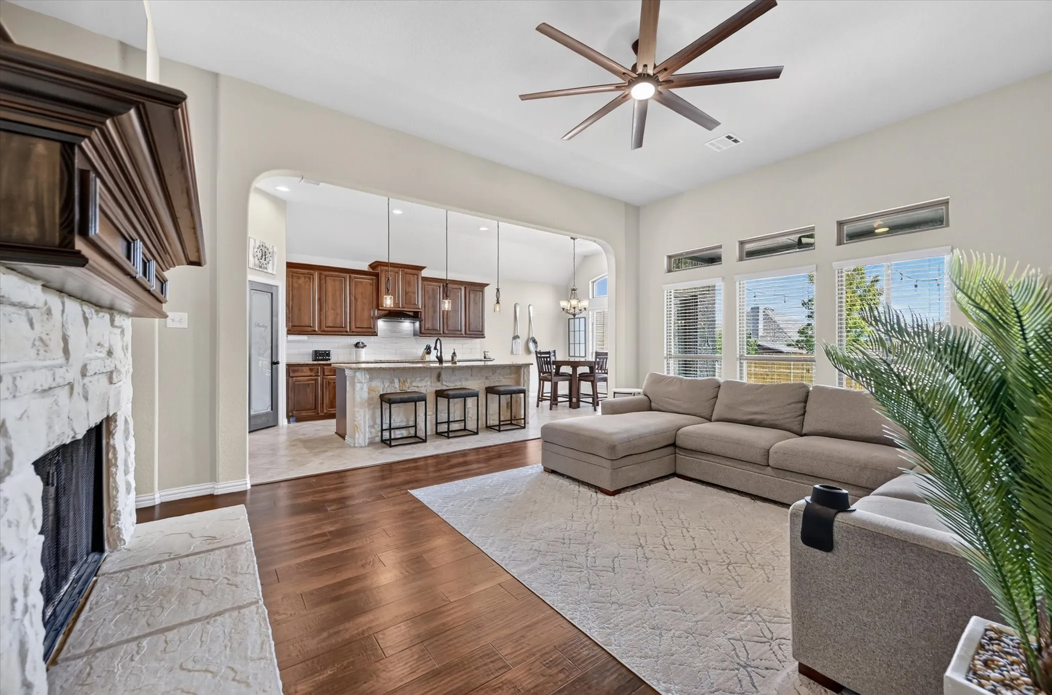 Open-concept living area featuring hardwood flooring, a large sectional layout, and abundant natural light from expansive windows
