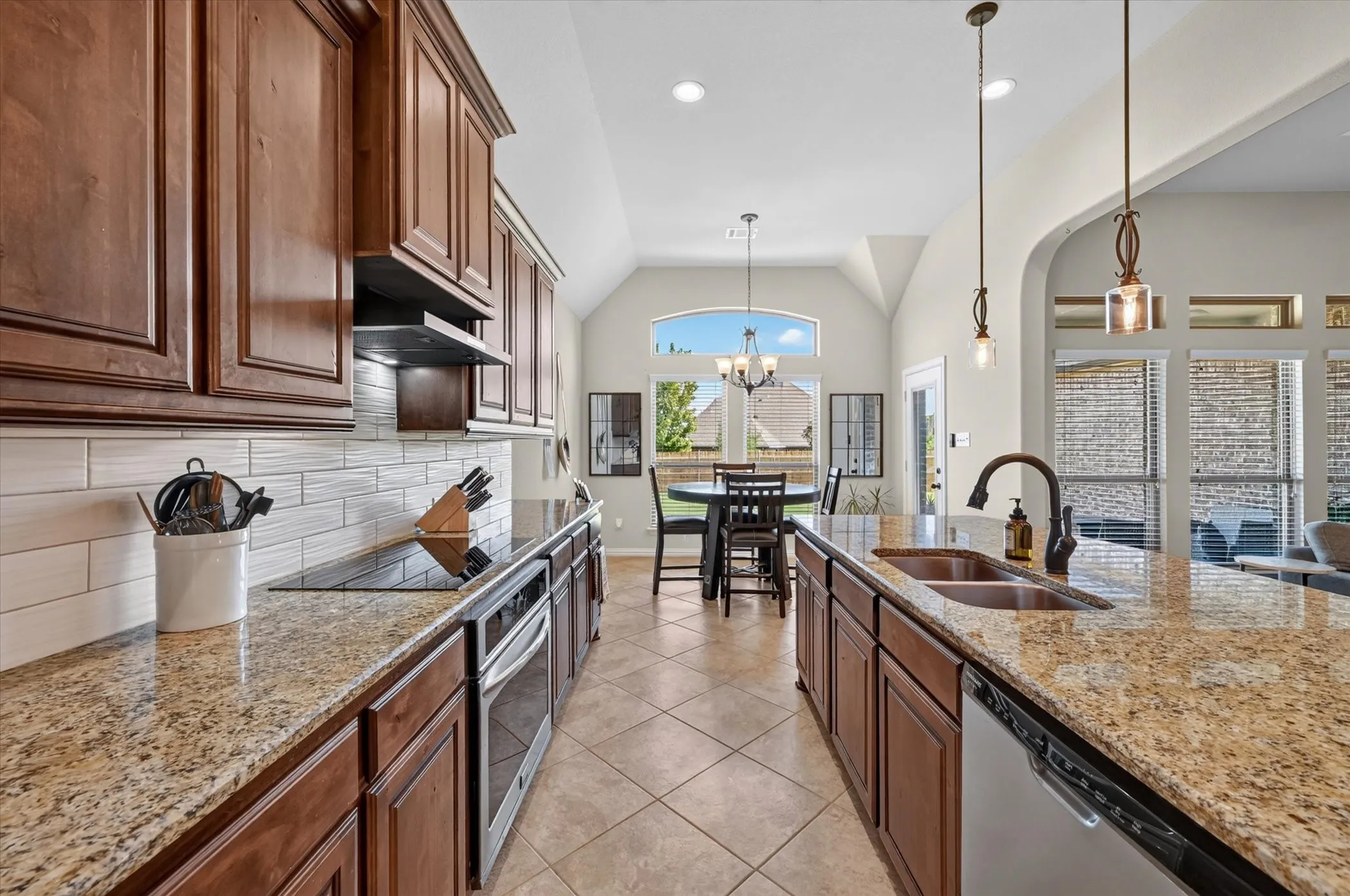 Kitchen featuring wood cabinetry, granite countertops, stainless steel appliances, and a tile backsplash