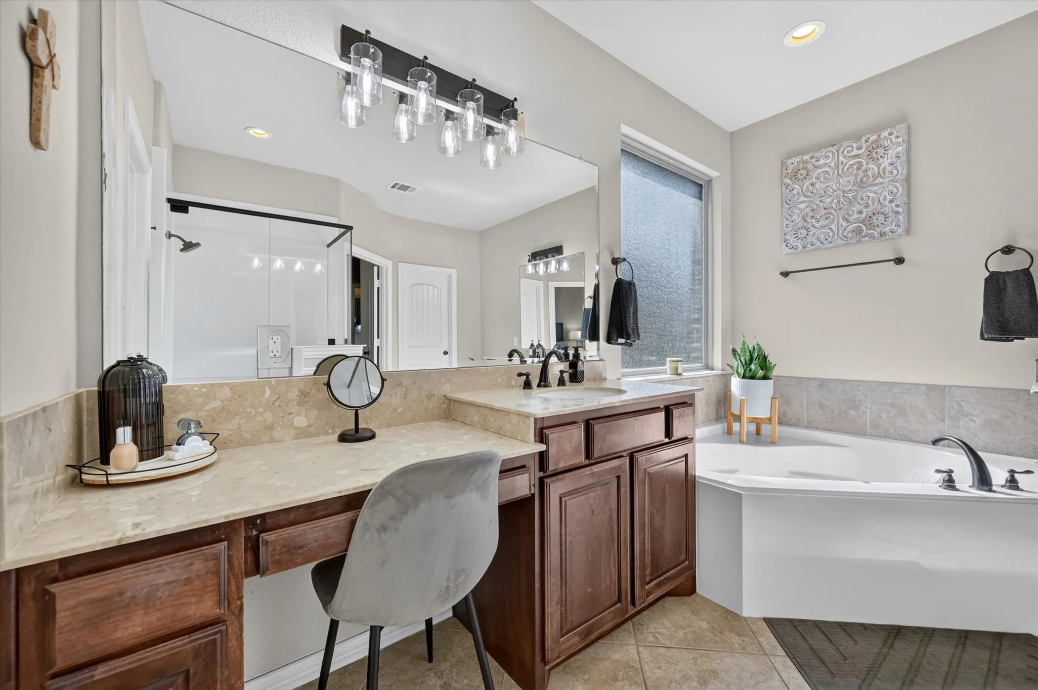 Spa-inspired primary bathroom featuring dual vanities with wood cabinetry, quartz countertops, and an undermount sink