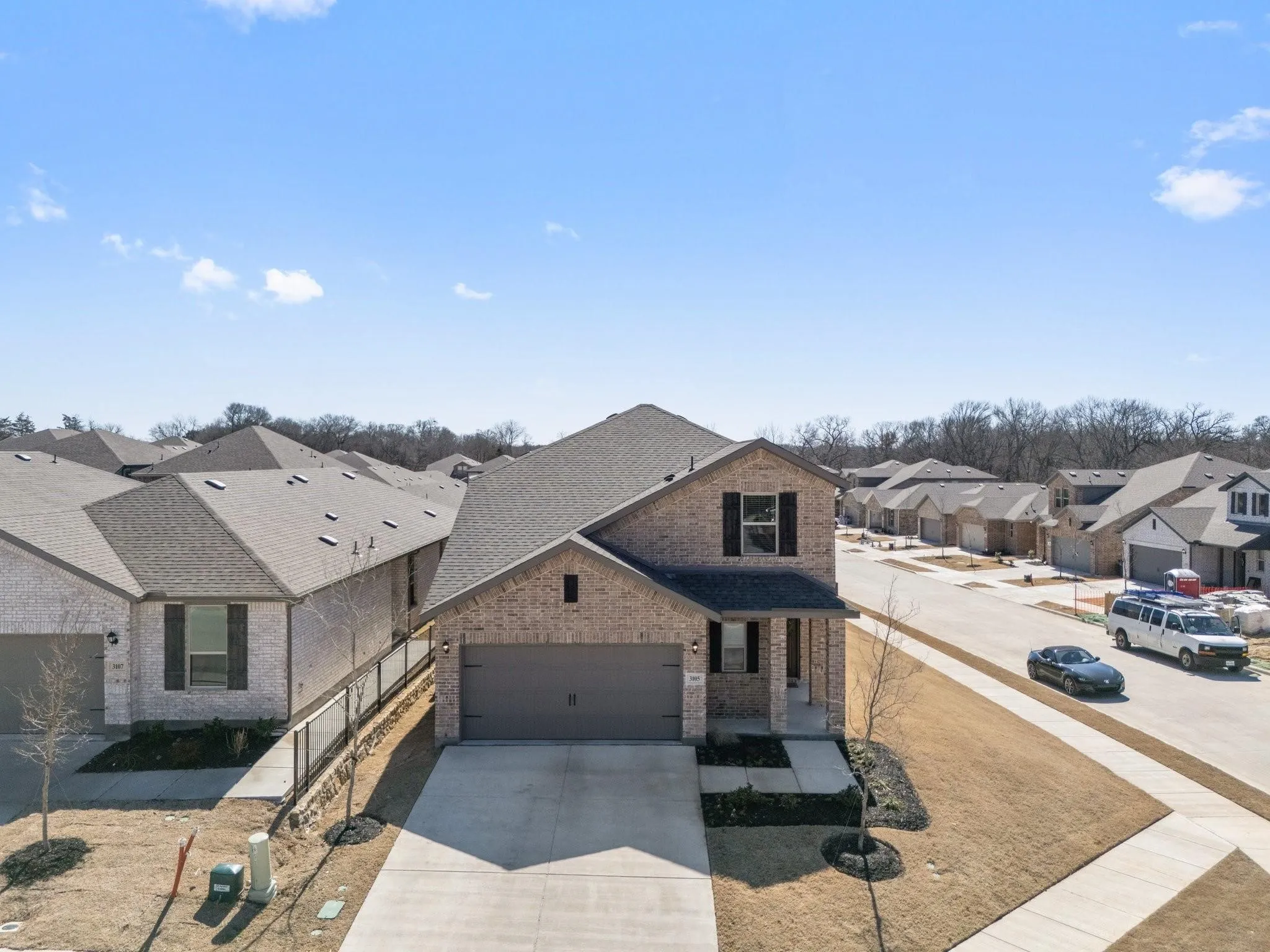 Traditional-style home with driveway, a shingled roof, an attached garage, brick siding, and a residential view
