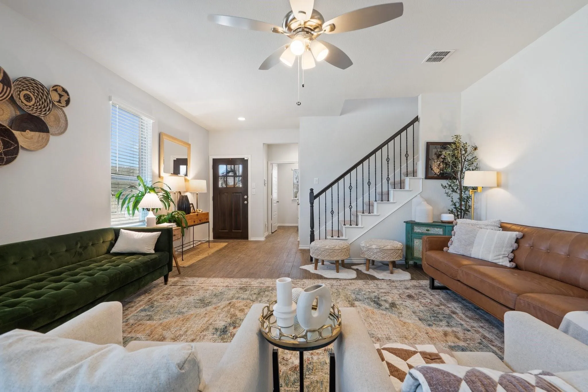 Living room with stairs, wood finished floors, ceiling fan, baseboards, and visible vents