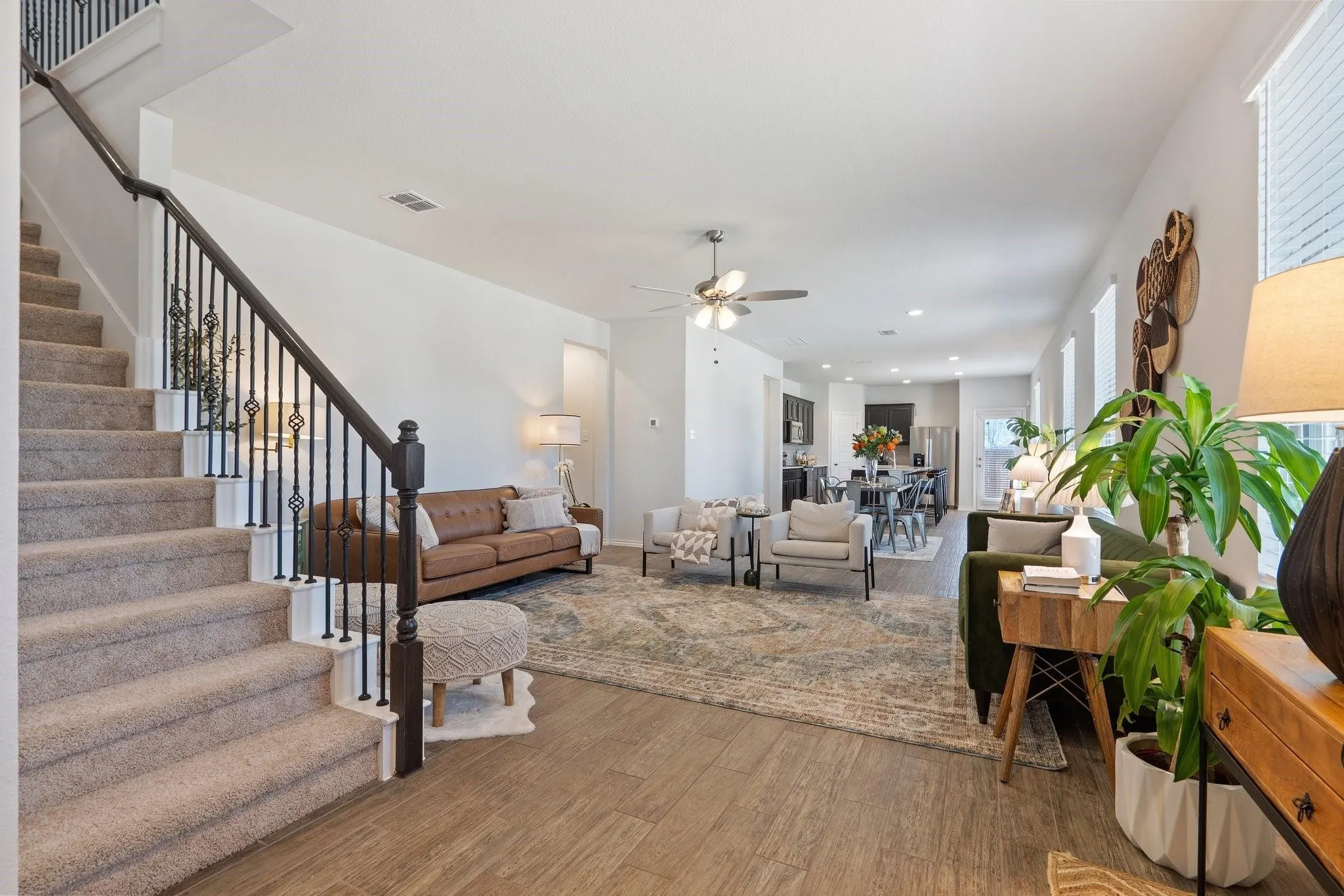 Living area featuring wood finished floors, visible vents, stairs, and a ceiling fan