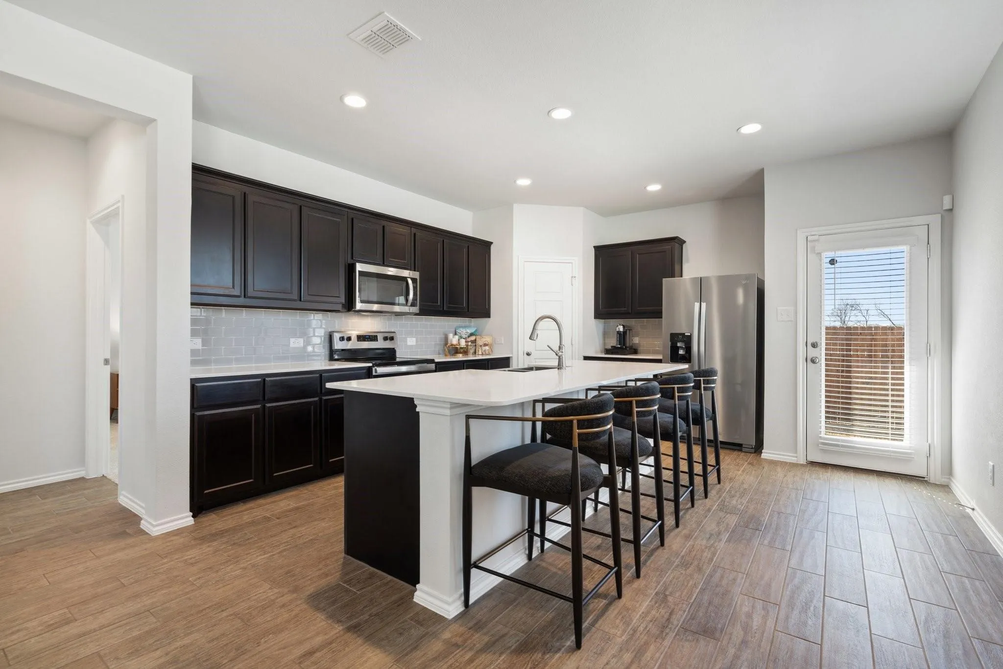 Kitchen with stainless steel appliances, visible vents, a sink, a center island with sink, and decorative backsplash