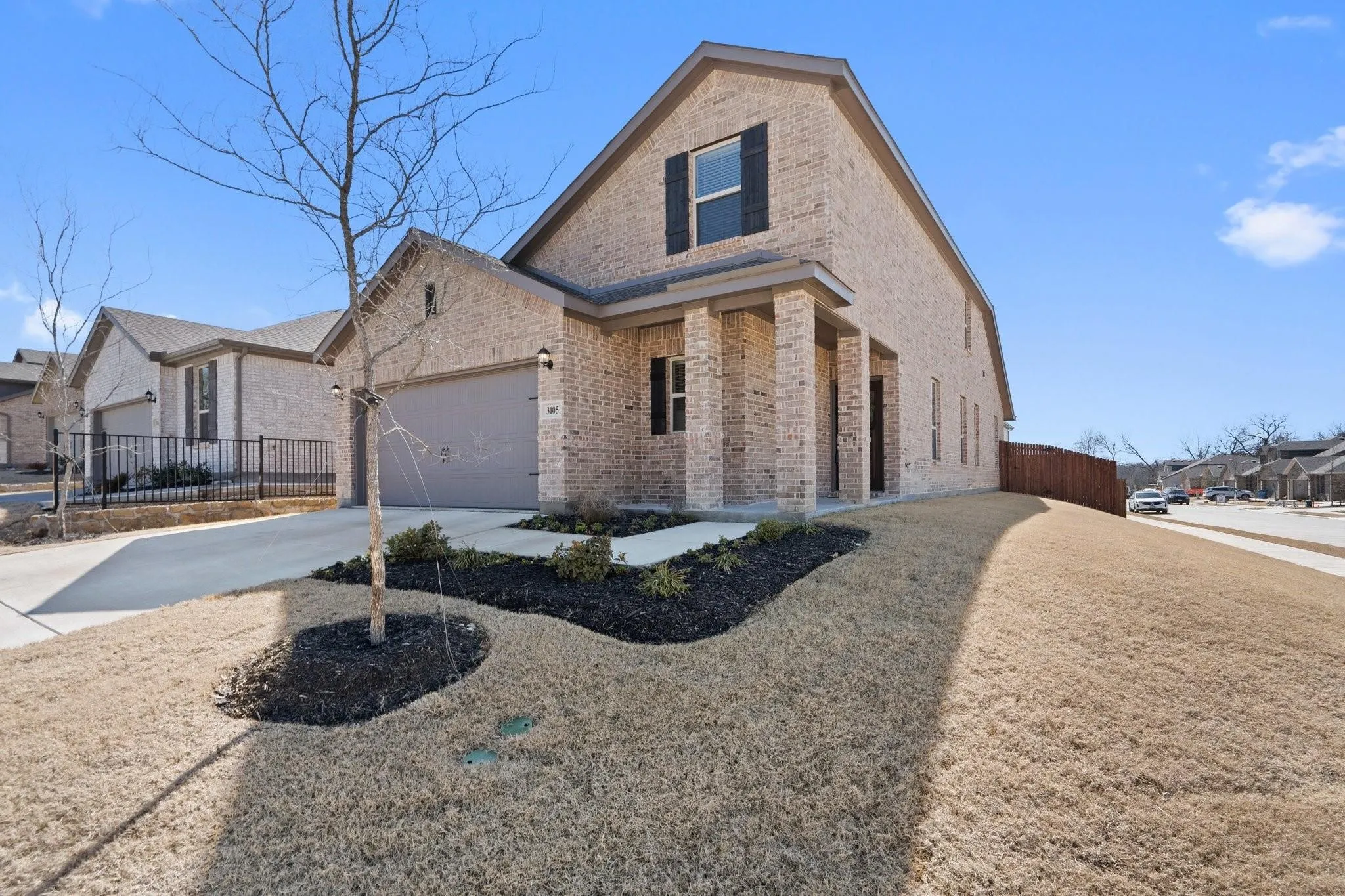 Traditional-style home with brick siding, fence, driveway, and a garage
