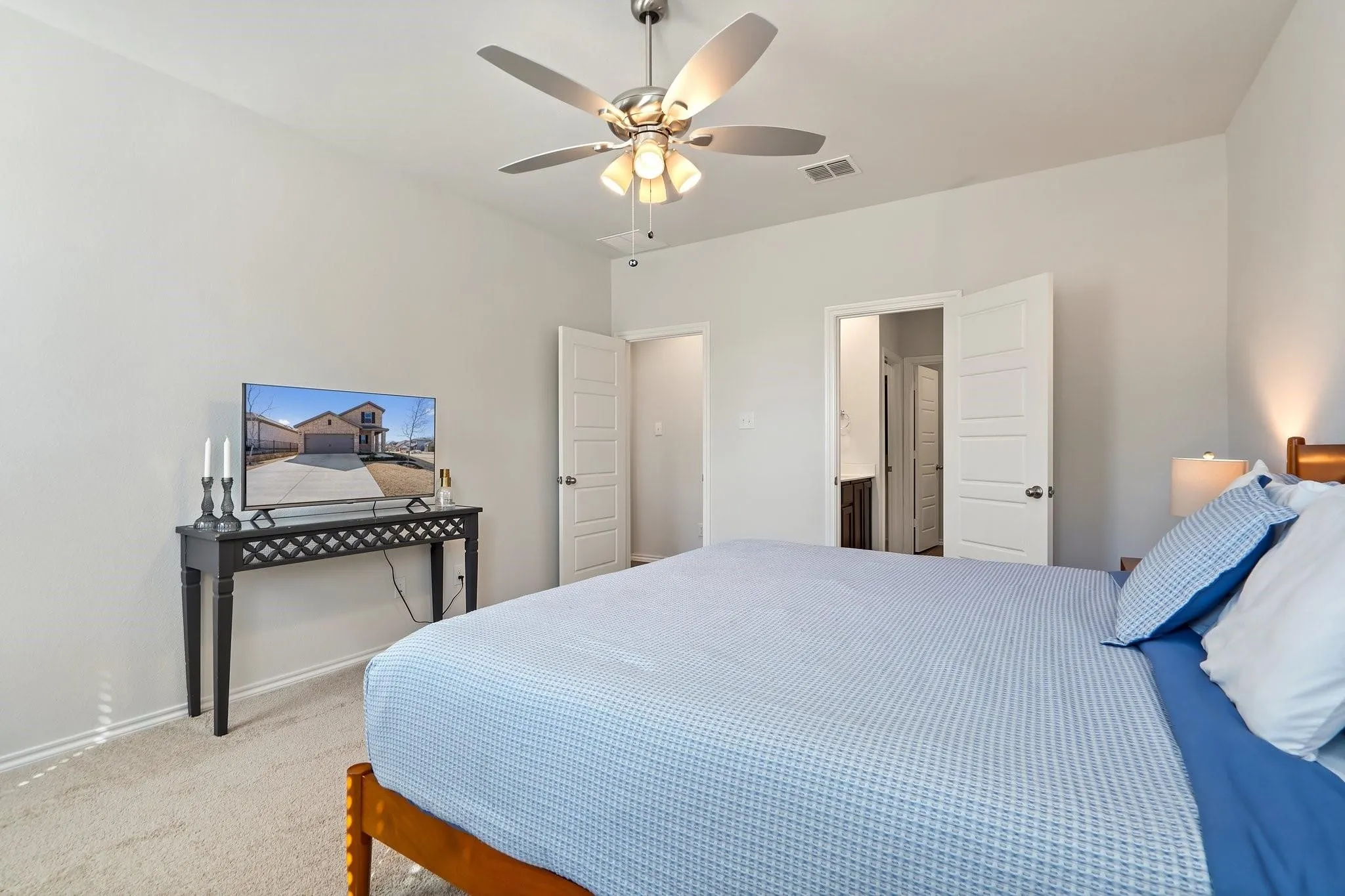 Carpeted bedroom featuring visible vents, a ceiling fan, and baseboards
