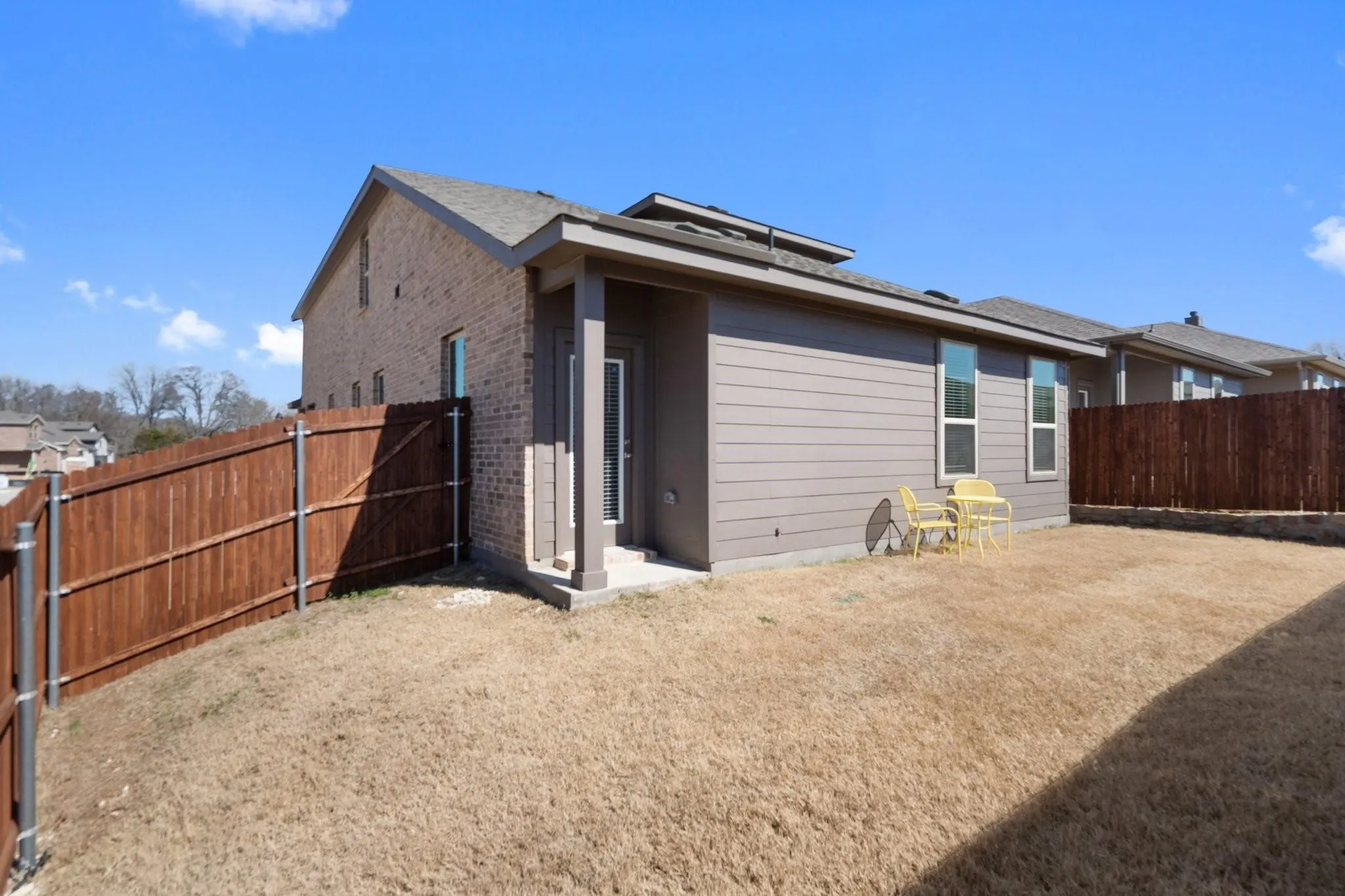 Rear view of house with a fenced backyard and brick siding