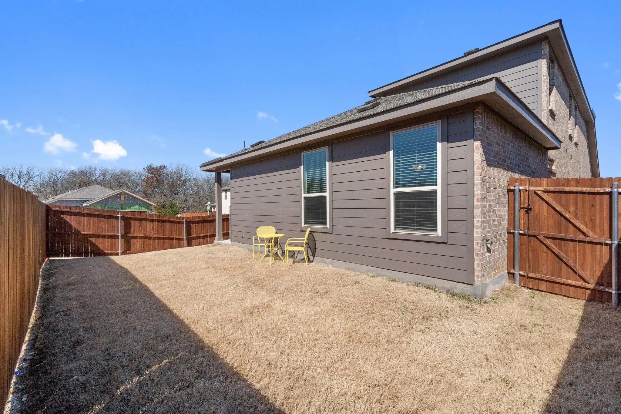Rear view of house featuring a gate, brick siding, and a fenced backyard
