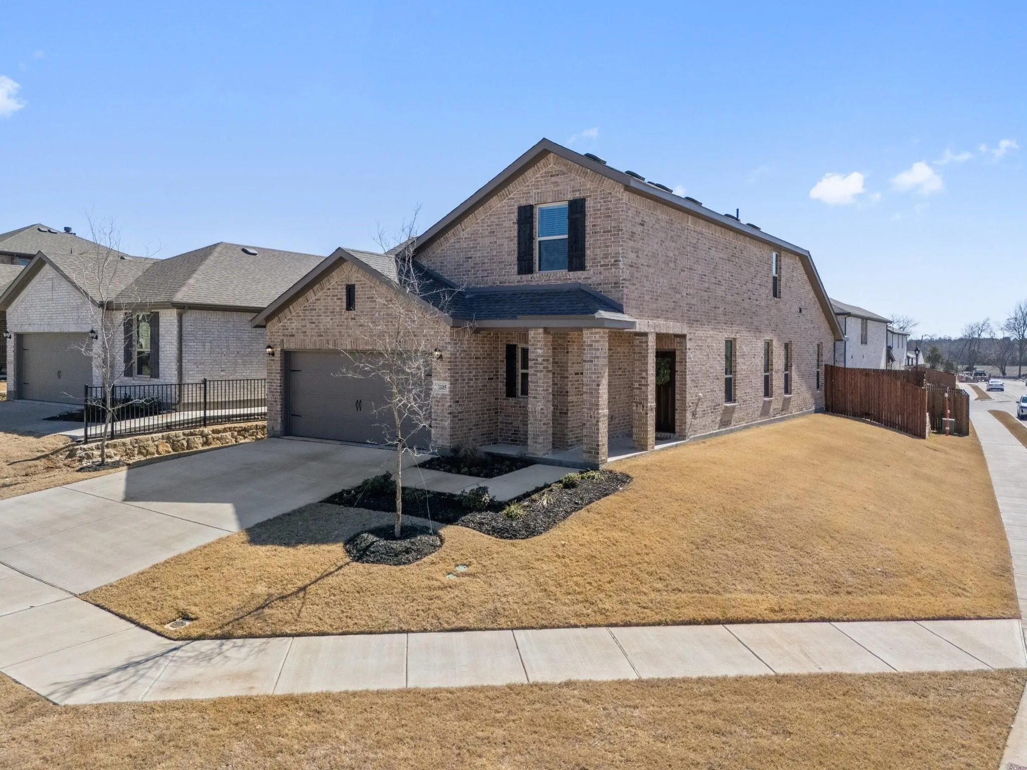 View of front of home featuring brick siding, driveway, a garage, and fence