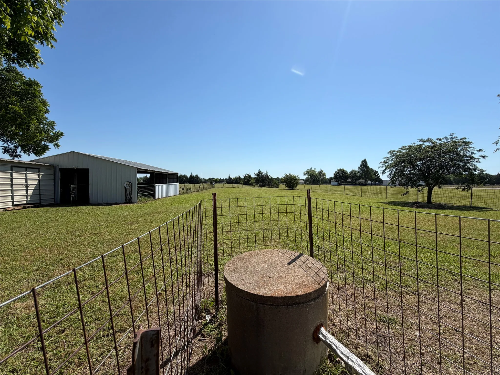 Expansive fenced pasture with a metal barn structure