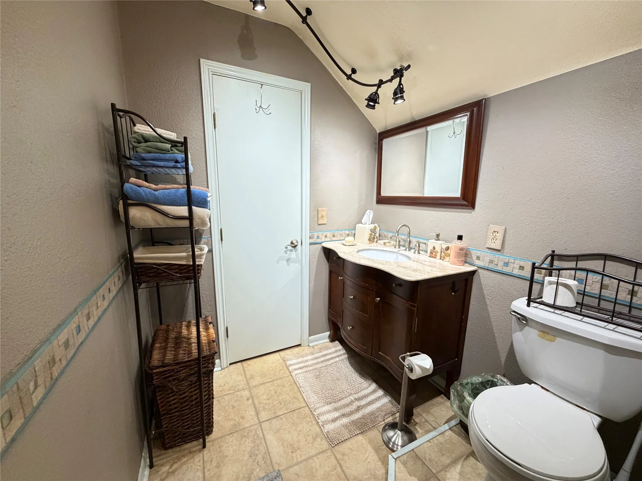 Vanity with a light-colored countertop, track lighting, and a framed mirror