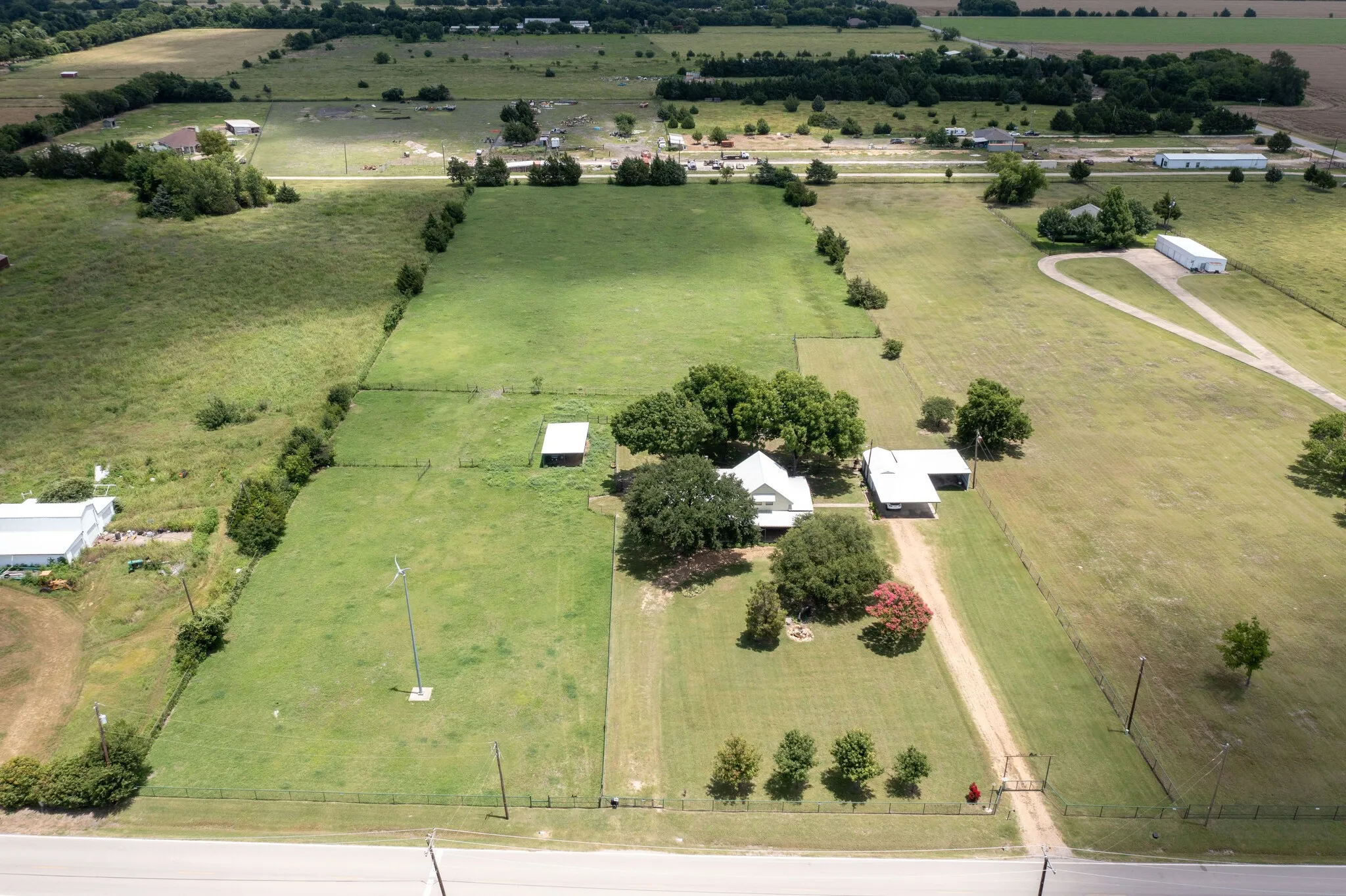 Expansive rural property featuring multiple outbuildings, mature tree-lined grounds, and gently rolling pastureland