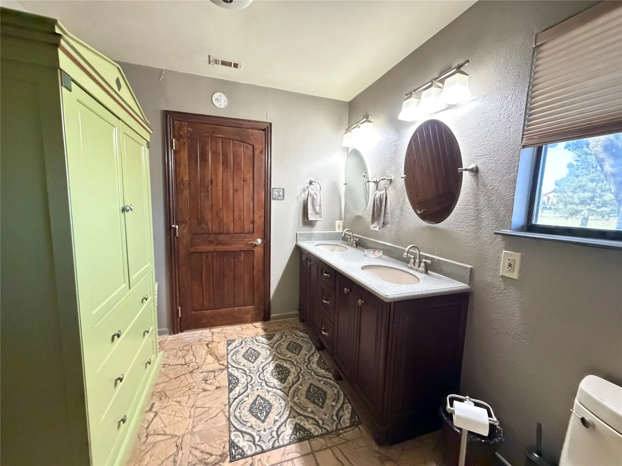 Dual vanity with undermount sinks, stone countertops, and individual oval mirrors