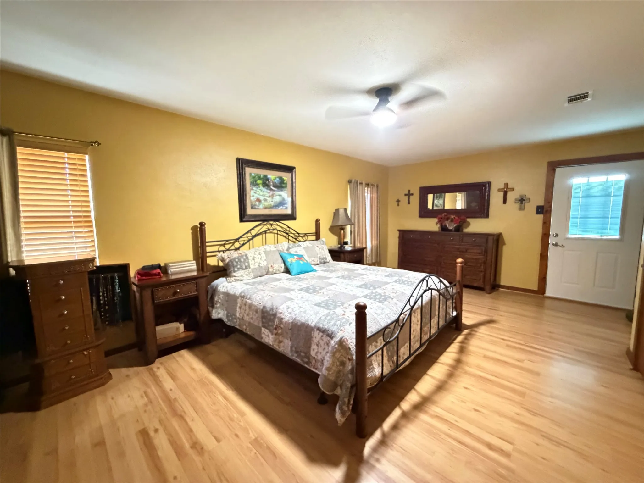 Warm interior with wood-finish flooring, a ceiling fan with integrated lighting, and a white door featuring a frosted glass insert