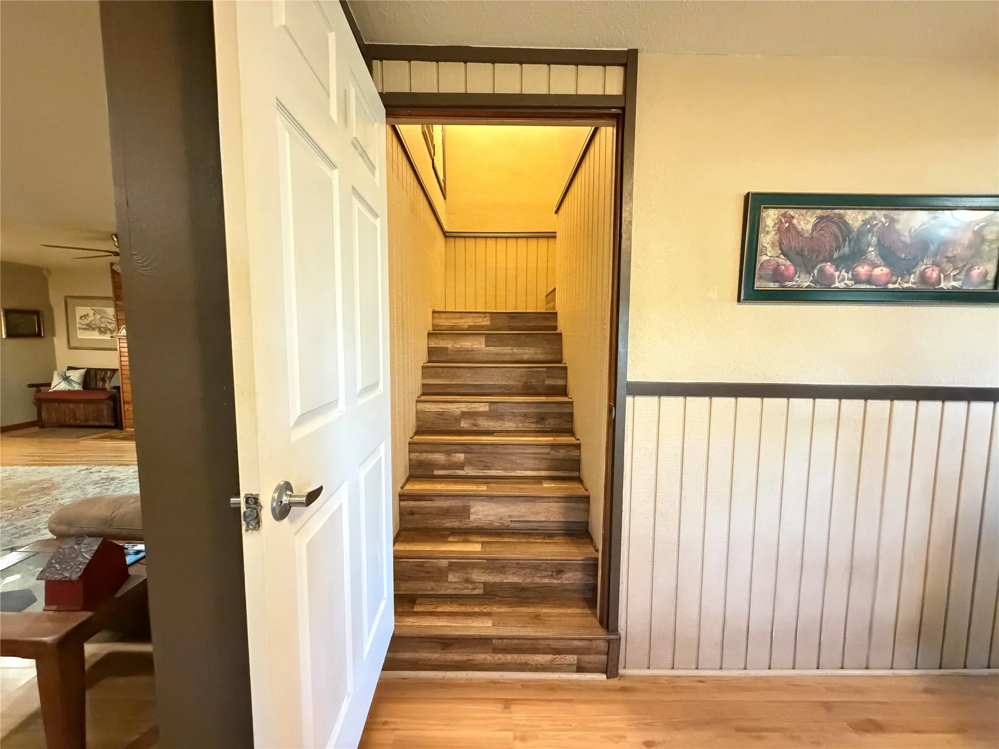 Staircase featuring wood-finish treads and risers, vertical paneling, and a painted wood handrail