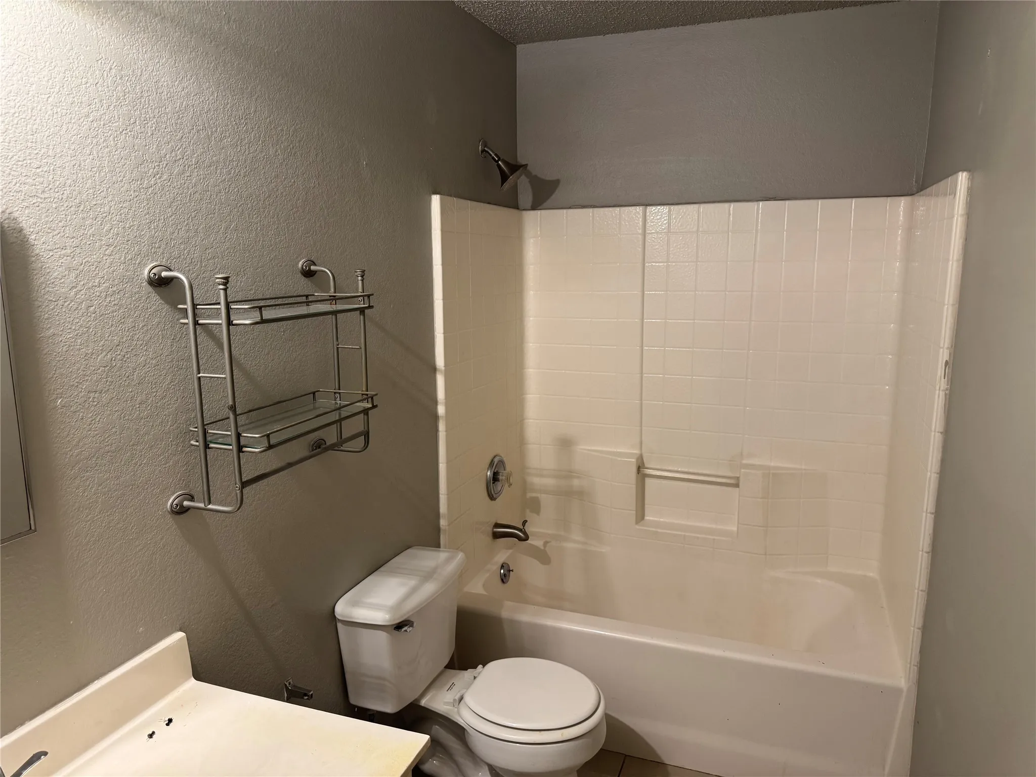 Full bath featuring a textured wall, shower / washtub combination, vanity, and a textured ceiling