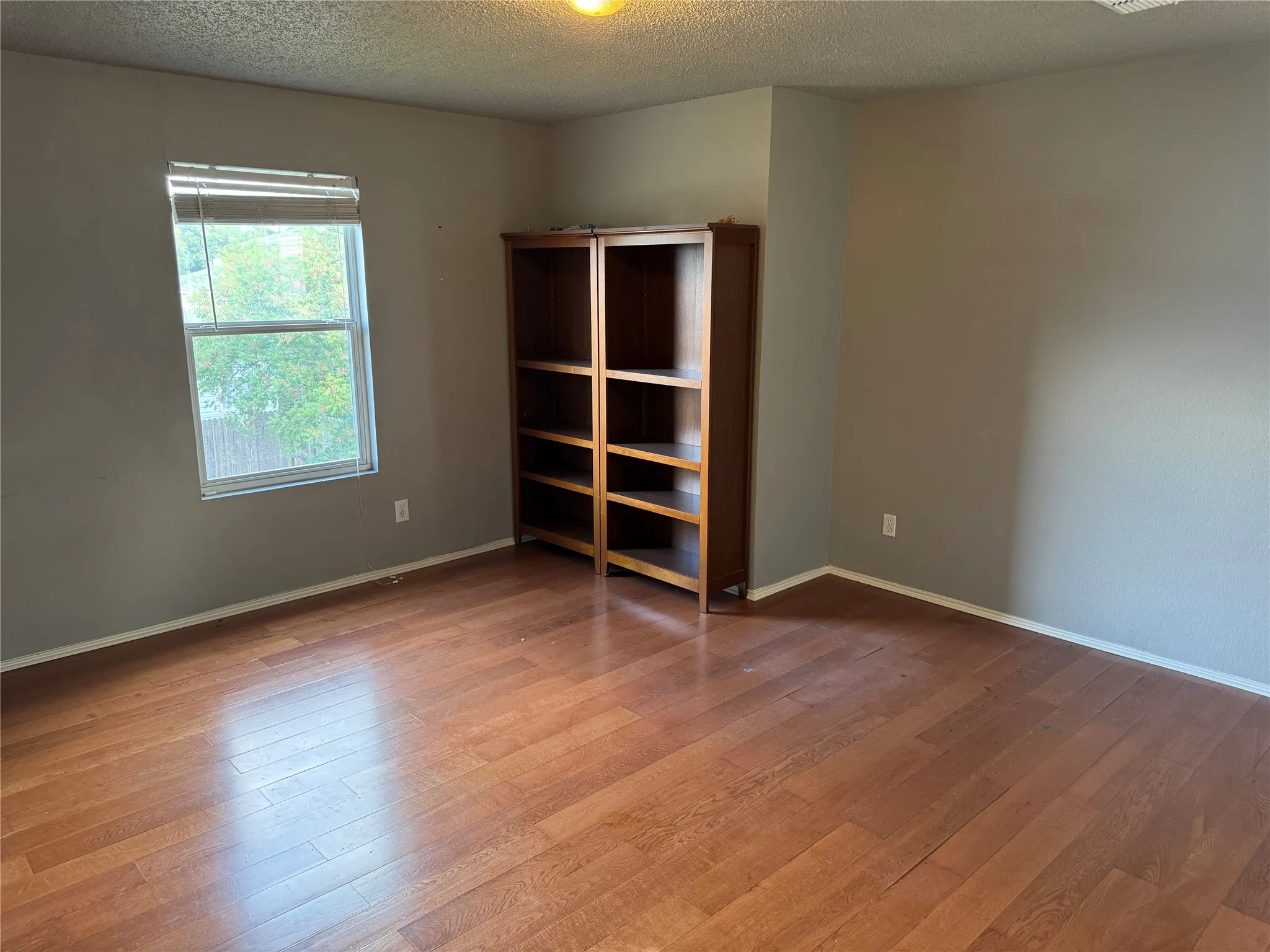 Empty room with a textured ceiling and wood finished floors