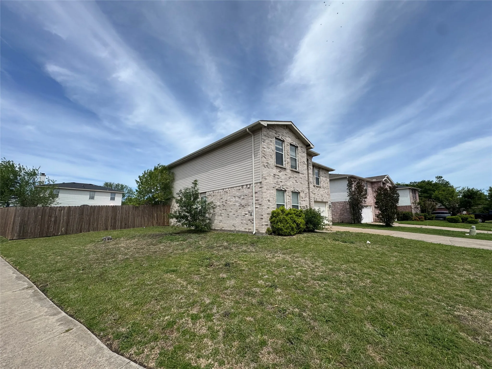 Two-story residence featuring a brick and siding exterior, multiple windows, an attached garage, and a concrete driveway