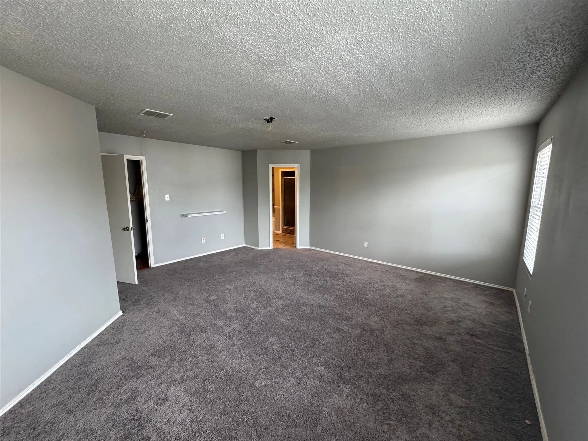 Spare room with dark carpet and a textured ceiling