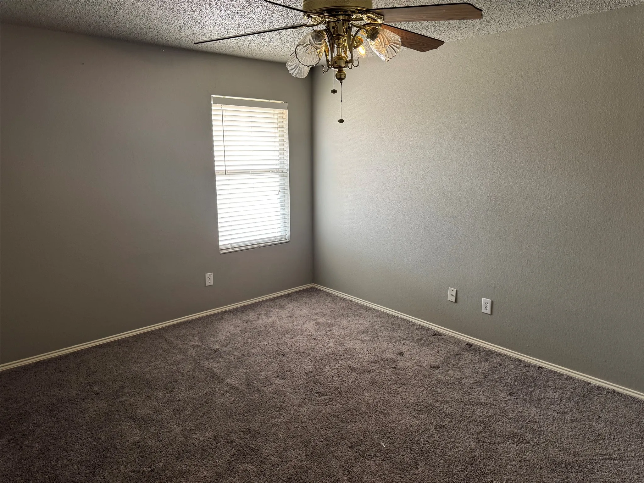 Spare room with a textured ceiling, carpet flooring, and ceiling fan