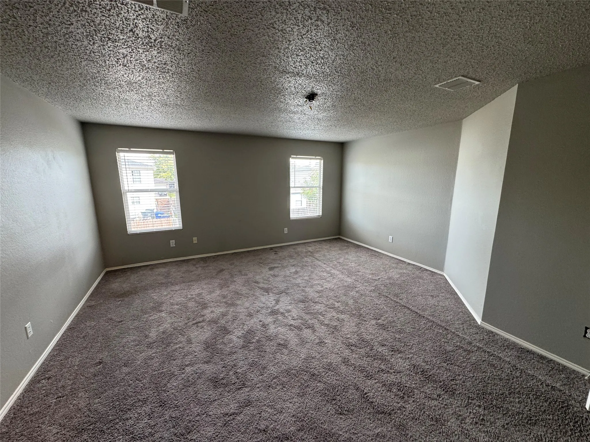 Carpeted spare room with a textured ceiling and a textured wall