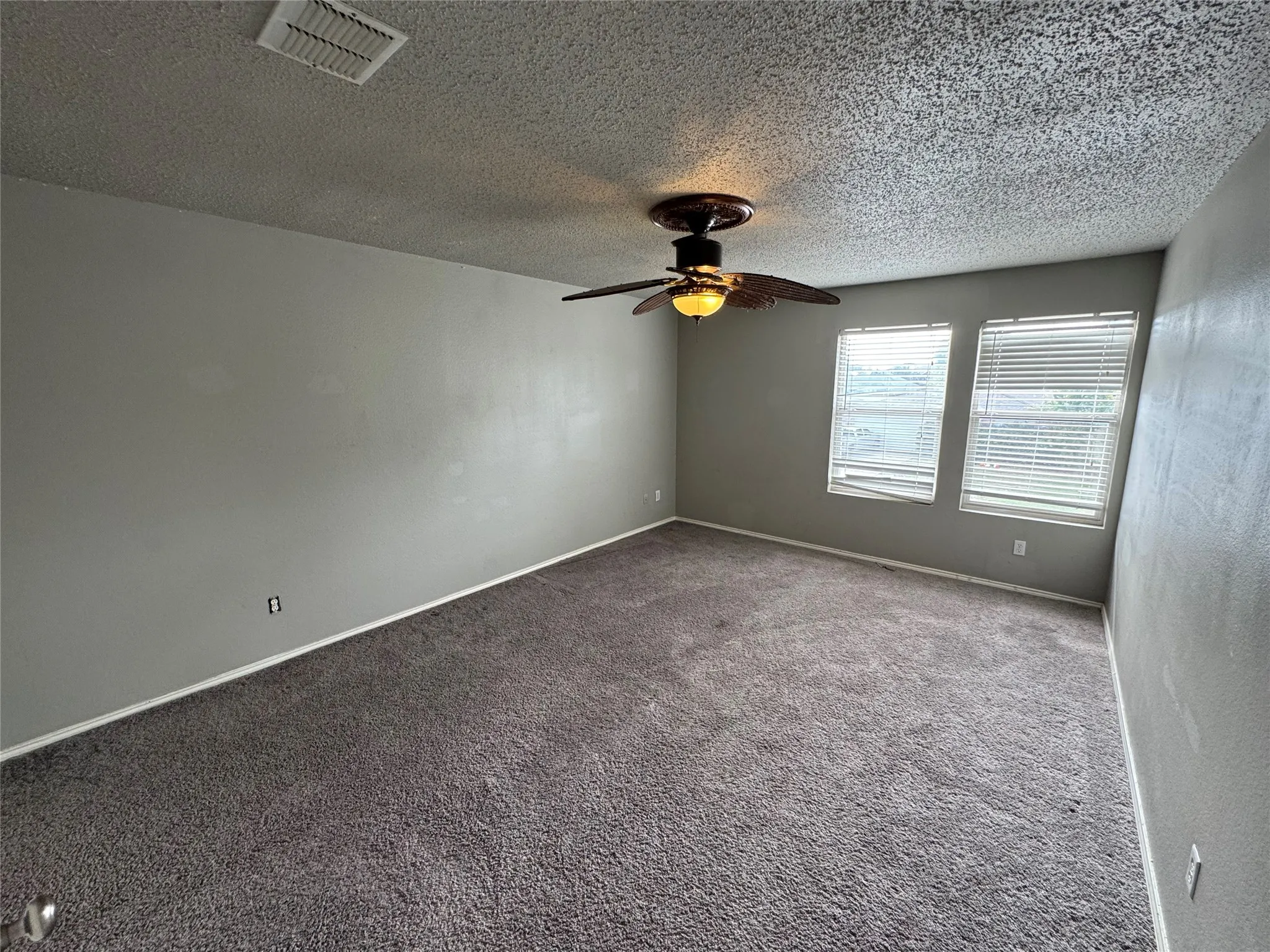 Spare room featuring carpet flooring, a textured ceiling, and ceiling fan
