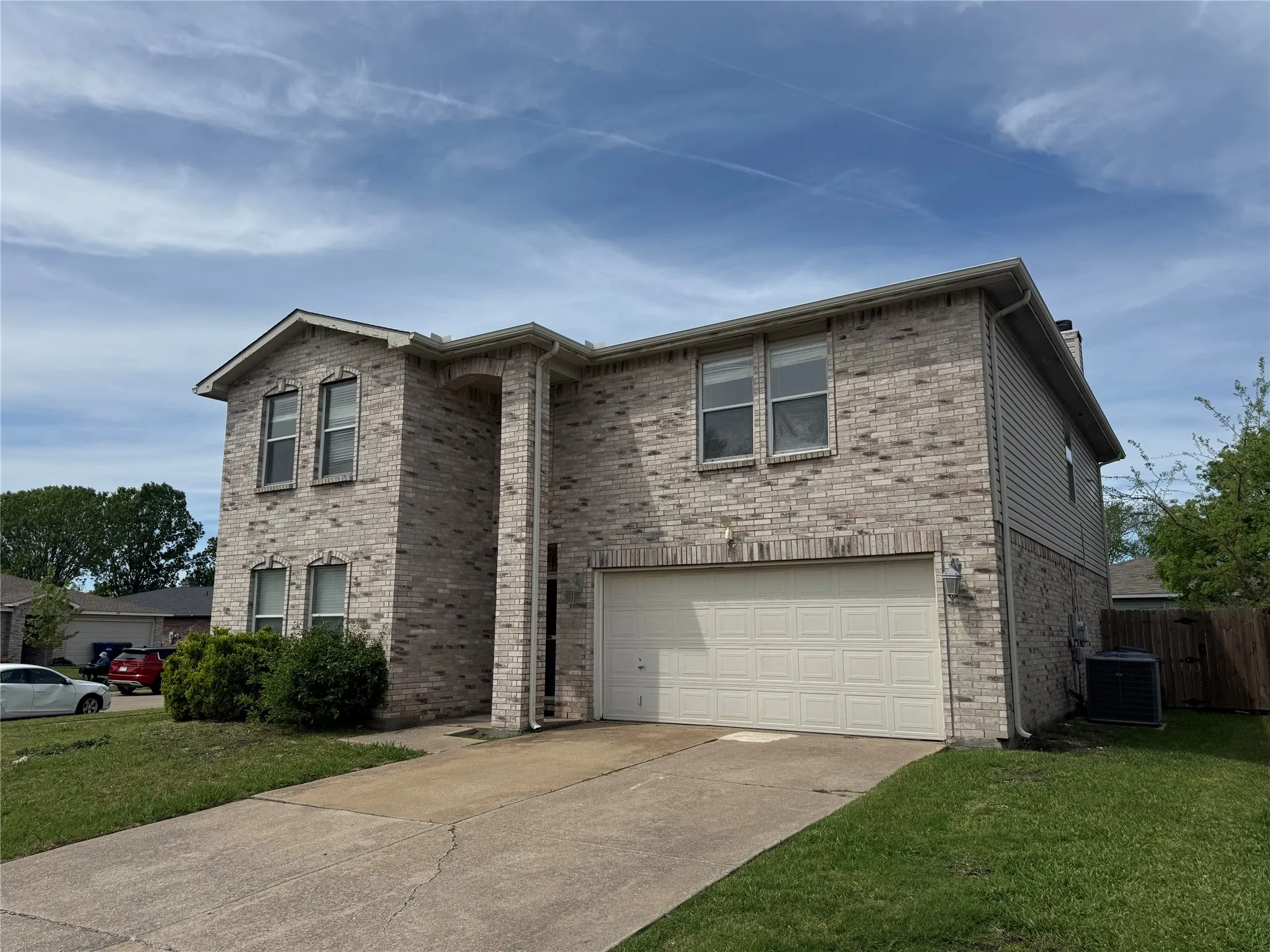 Two-story brick and siding residence featuring a two-car garage with a panel door