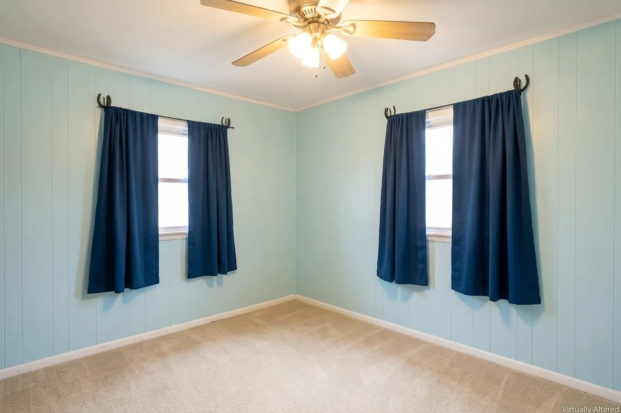 Wall paneling, light-toned carpeting, ceiling fan with integrated lighting, and two windows