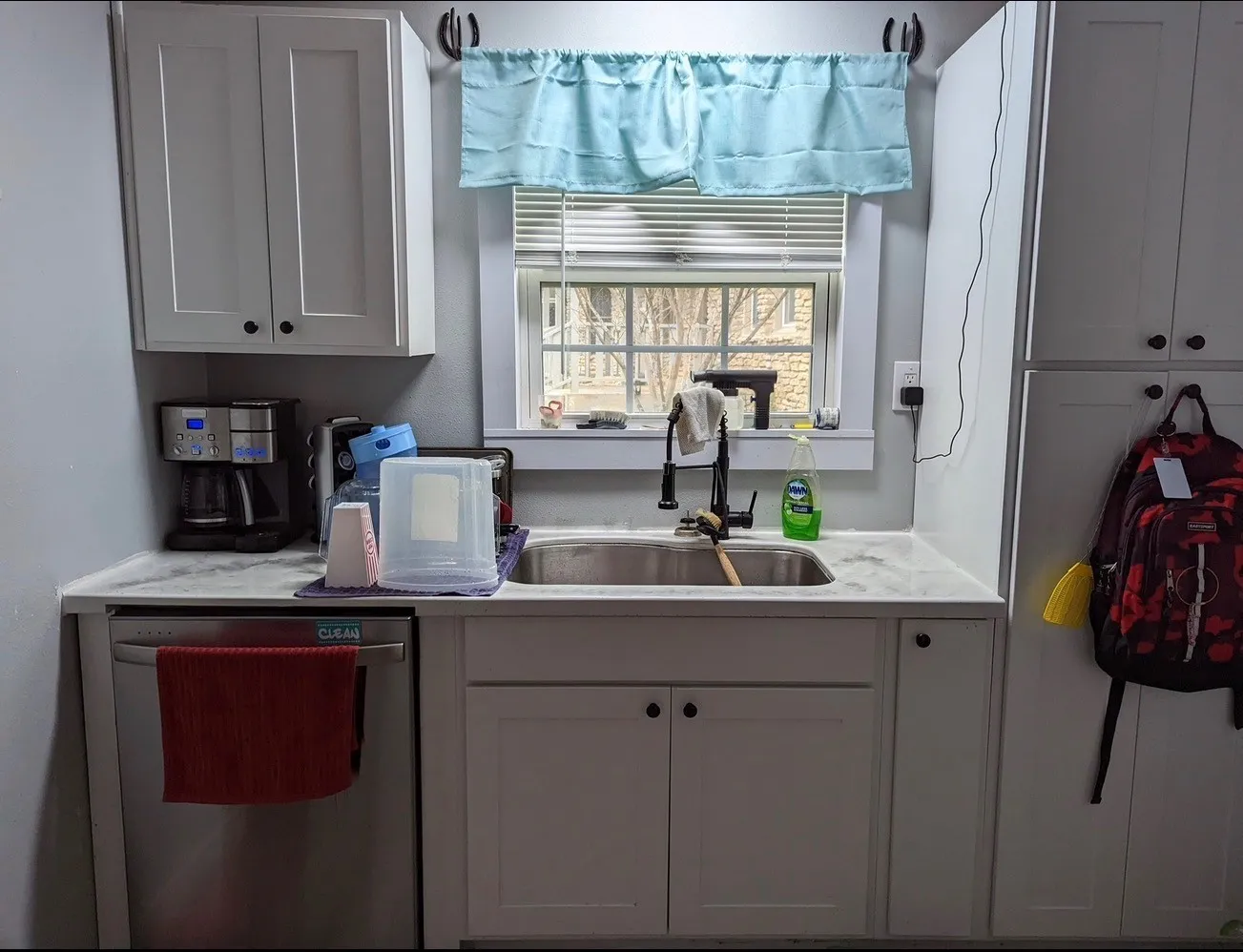 Kitchen featuring white cabinetry, a stainless steel sink with a matte black faucet, and light-toned countertops