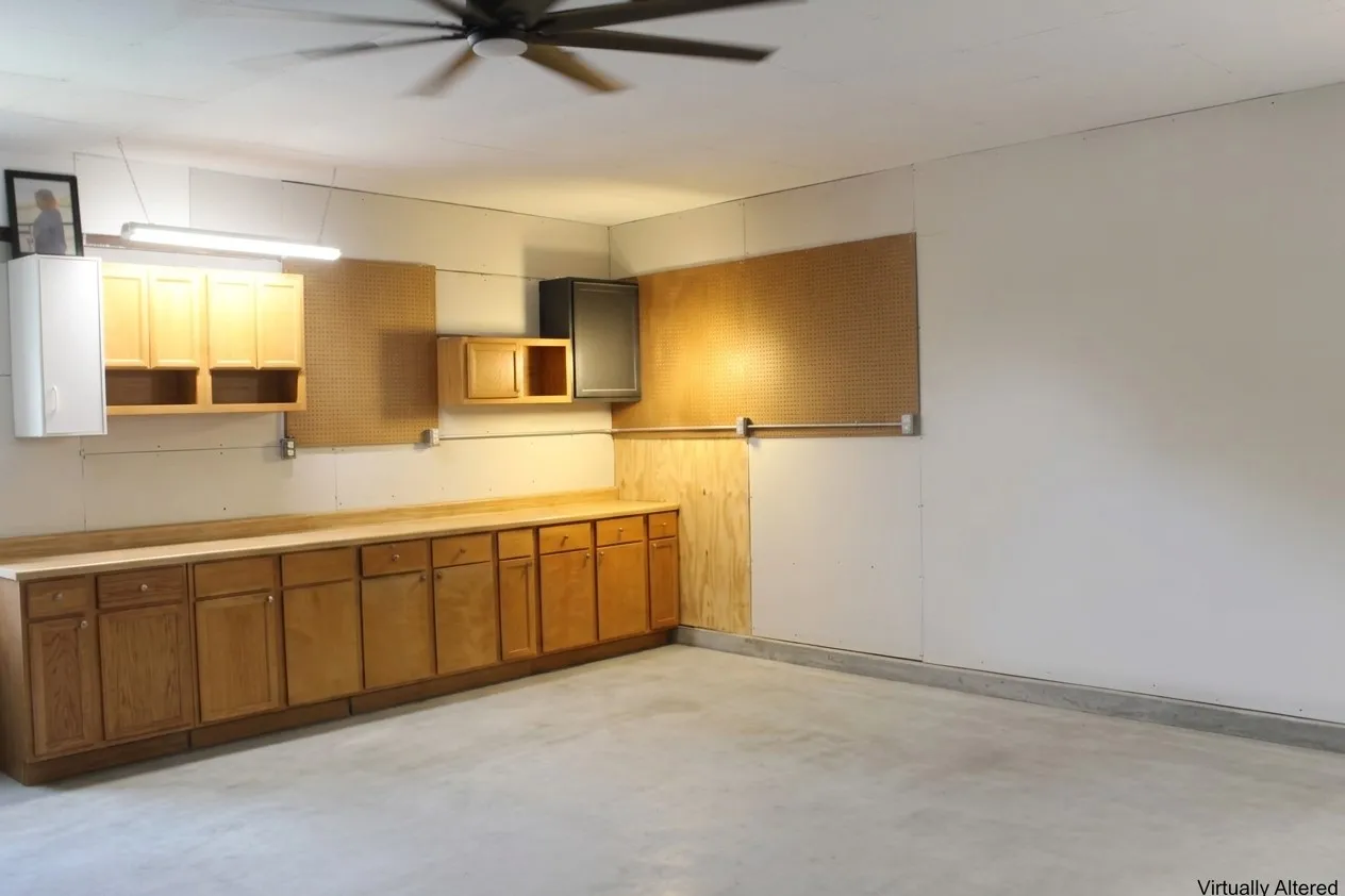 Concrete flooring, built-in lower cabinetry, built-in upper cabinetry, fluorescent lighting, and a ceiling fan