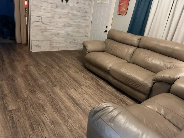 Wood-finish flooring throughout, white paneled accent wall, and a white entry door with a black handle