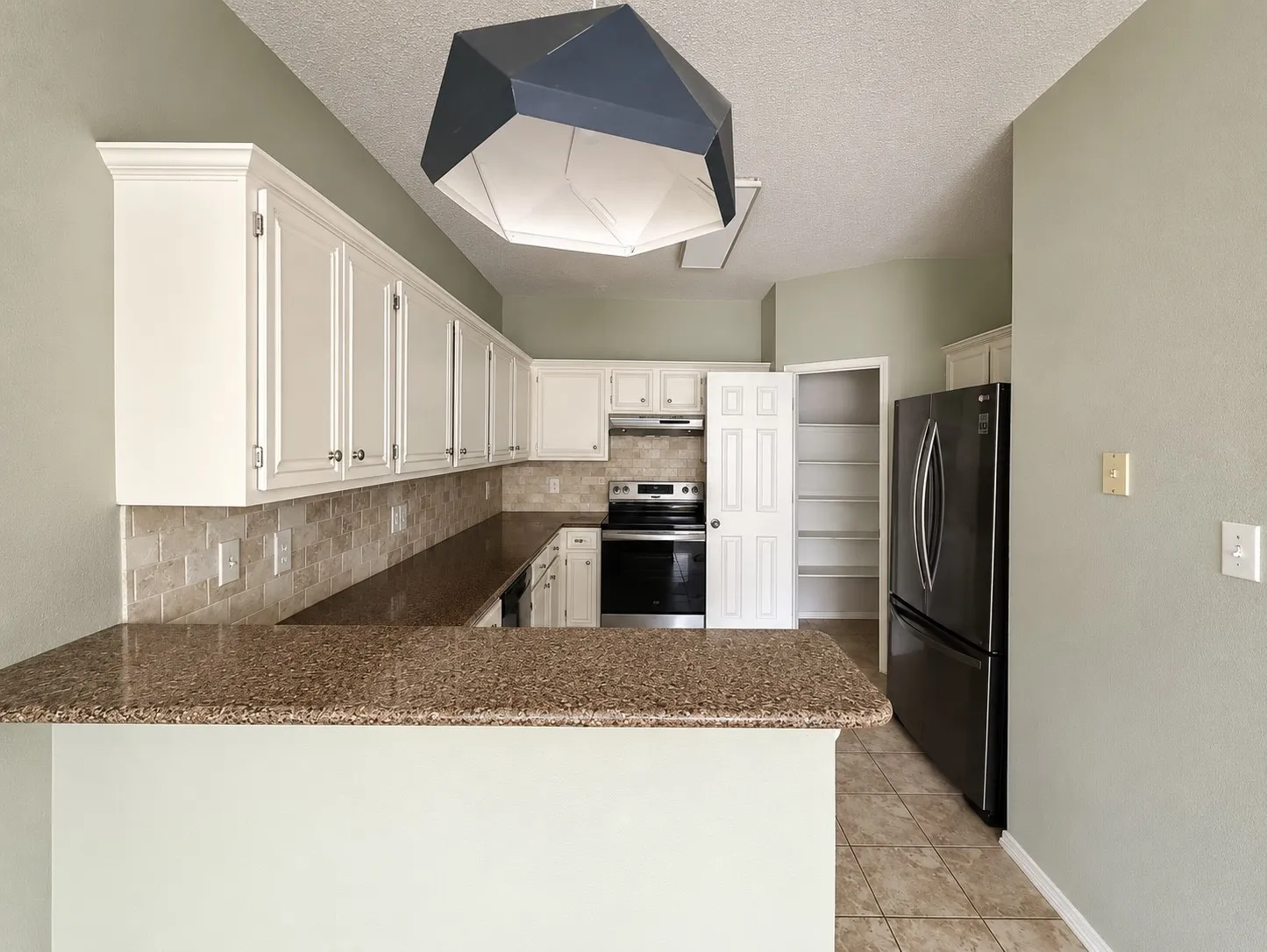 Kitchen featuring a breakfast bar with stone-finish countertop, light-toned cabinetry, tile backsplash, stainless steel appliances, and tile flooring