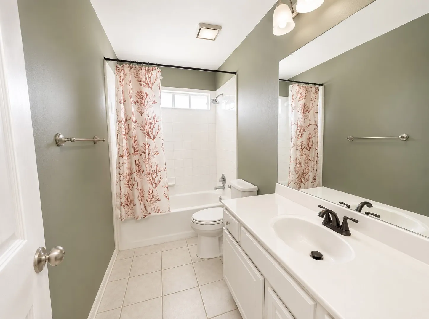 Galley-style bathroom featuring dual vanity with white cabinetry, ceramic tile flooring, and brushed nickel hardware