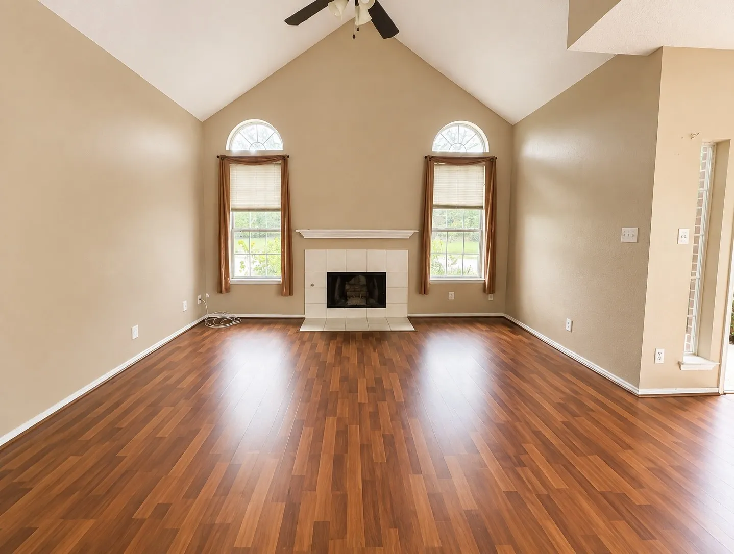 Soaring vaulted ceilings with exposed wood beams and a ceiling fan create an open, light-filled great room