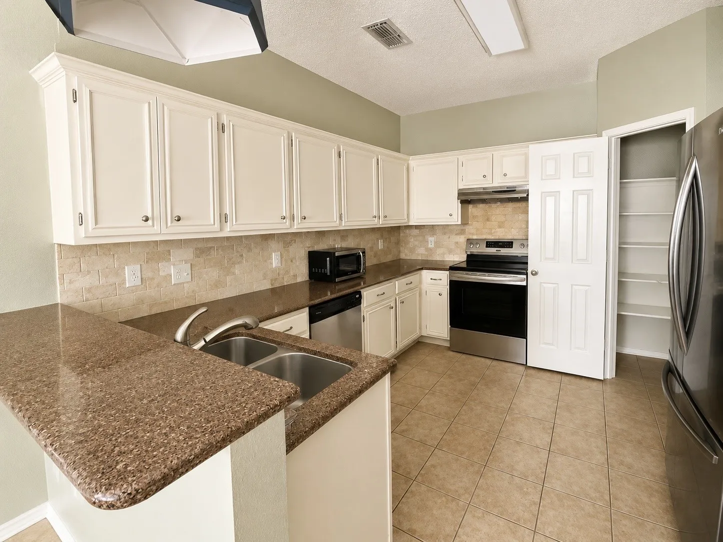 Kitchen featuring white cabinetry, stone-look countertops, a tile backsplash, and stainless steel appliances