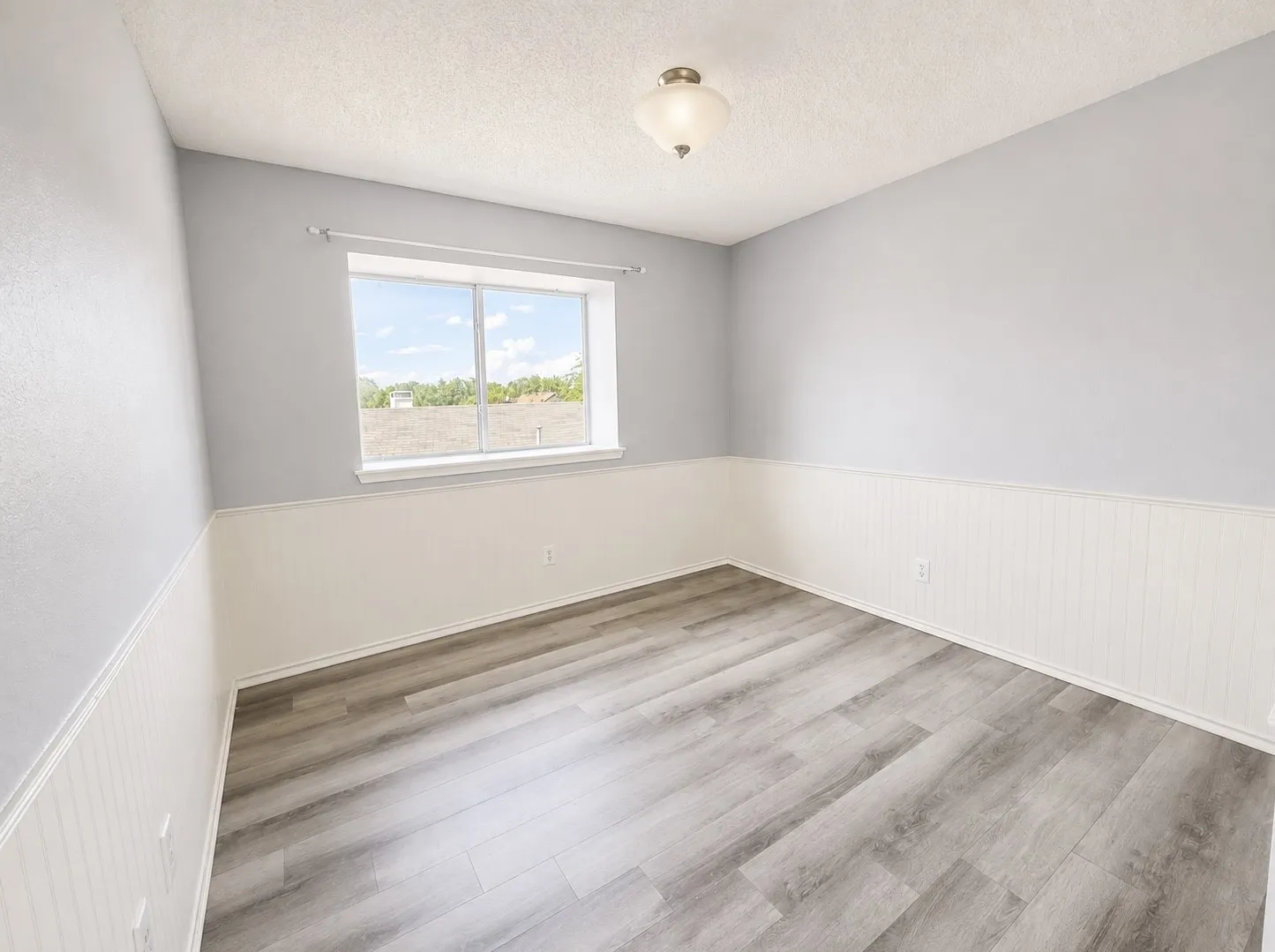 Wood-finish flooring, white beadboard wainscoting, light gray painted walls, and a ceiling-mounted light fixture