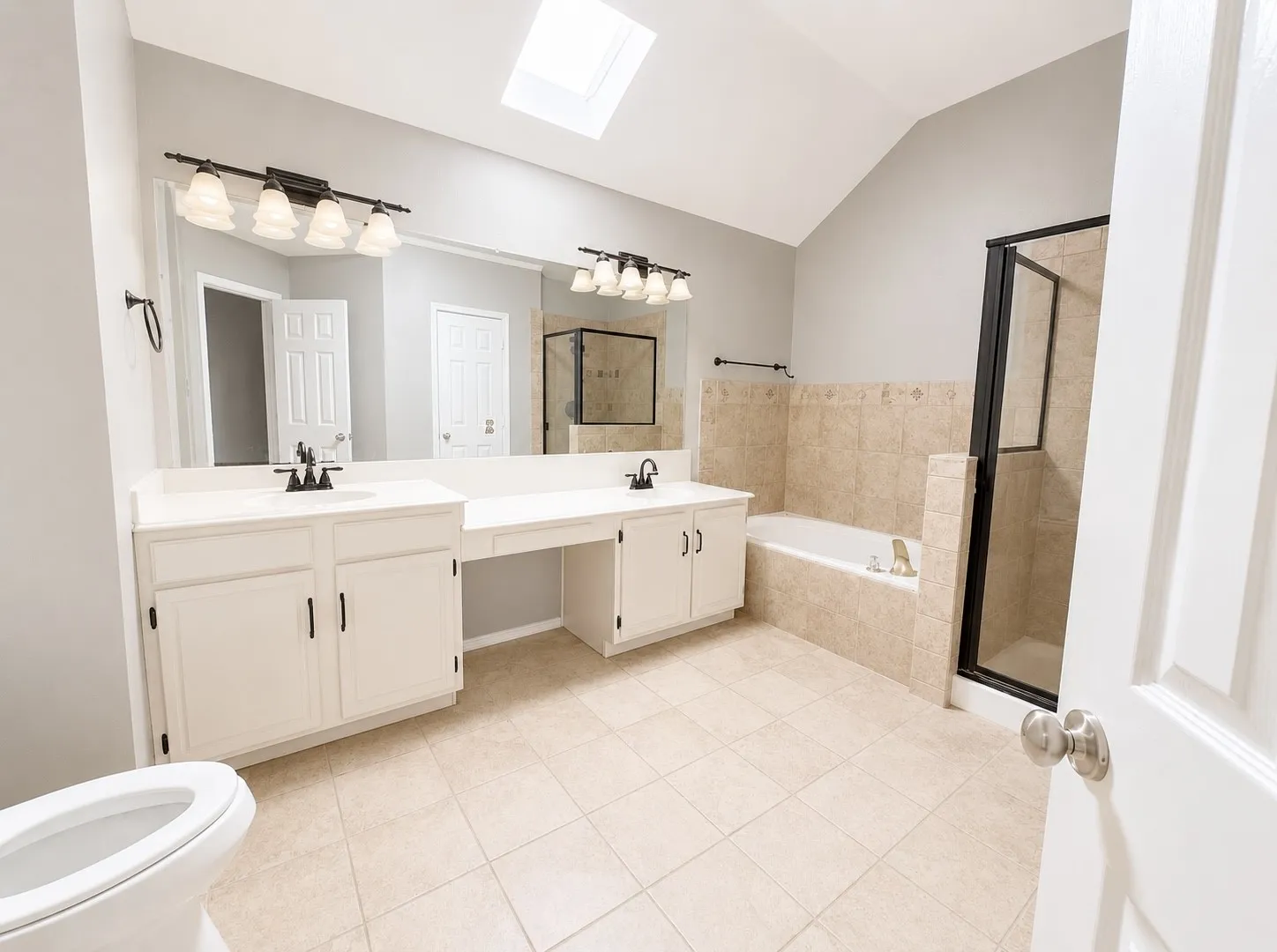 Dual vanity with integrated sinks, a built-in makeup counter, tiled soaking tub, and a separate glass-enclosed shower
