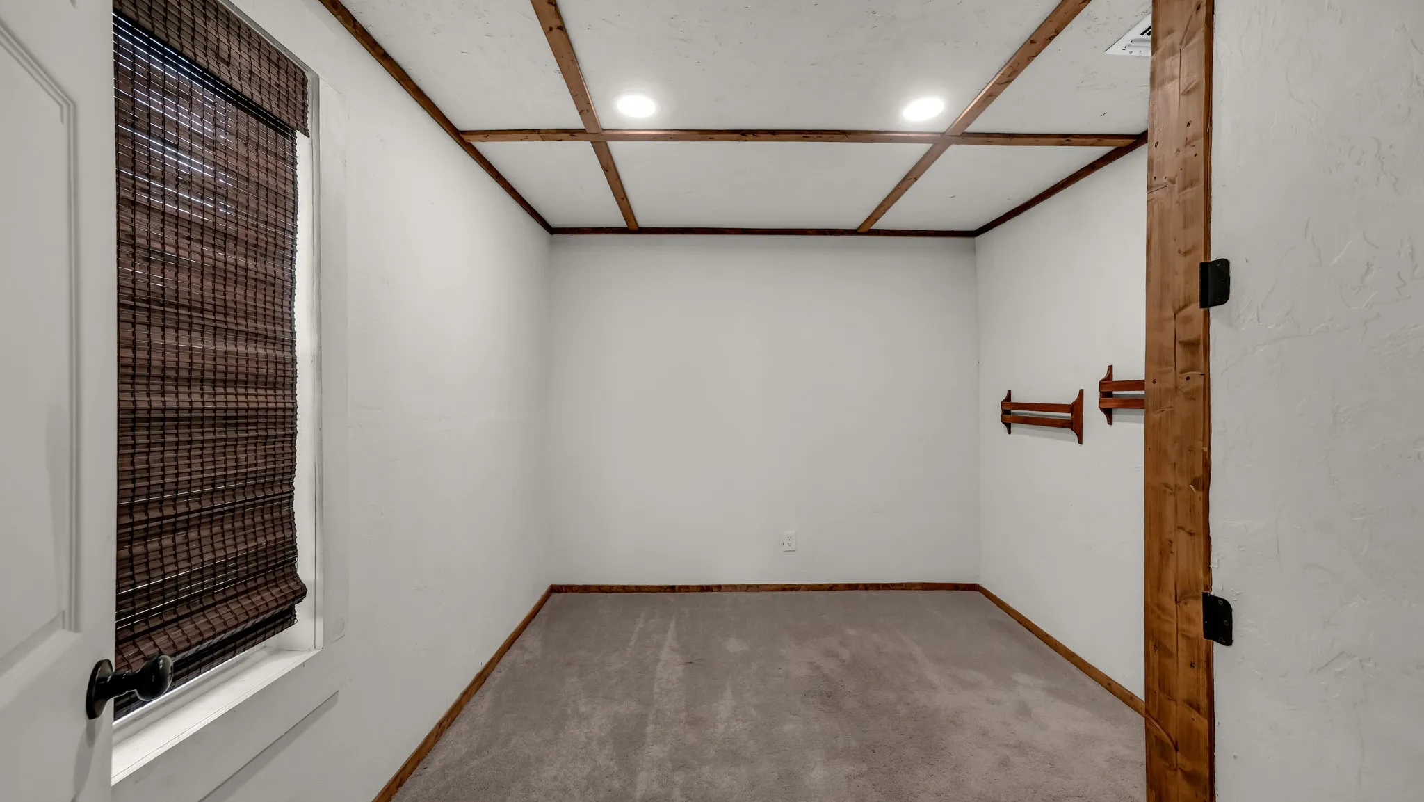 Recessed lighting illuminates a coffered ceiling with wood-finish beams