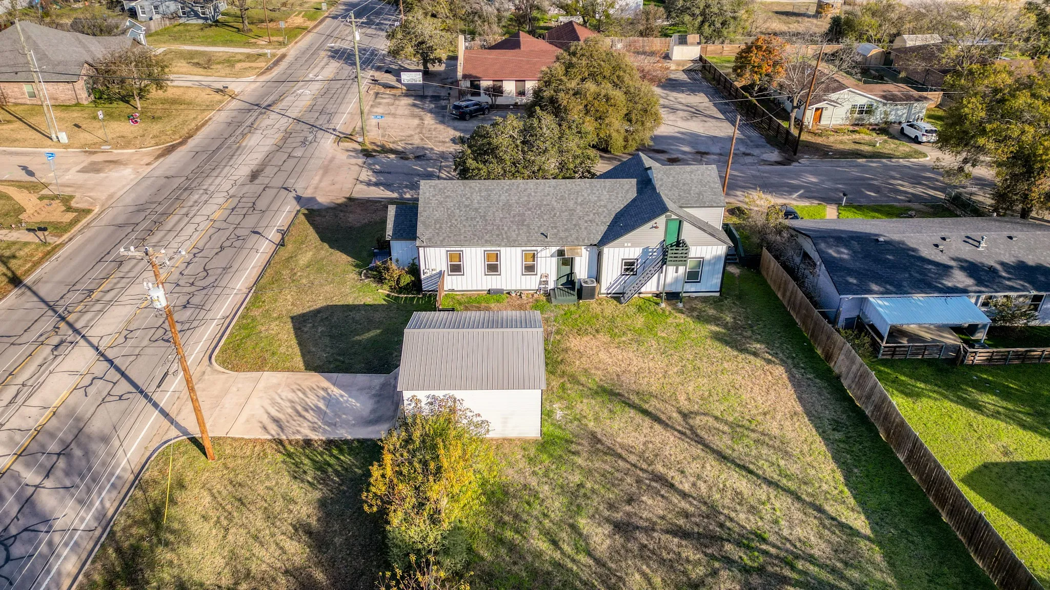 Expansive lot featuring a detached auxiliary building, mature trees, and street access