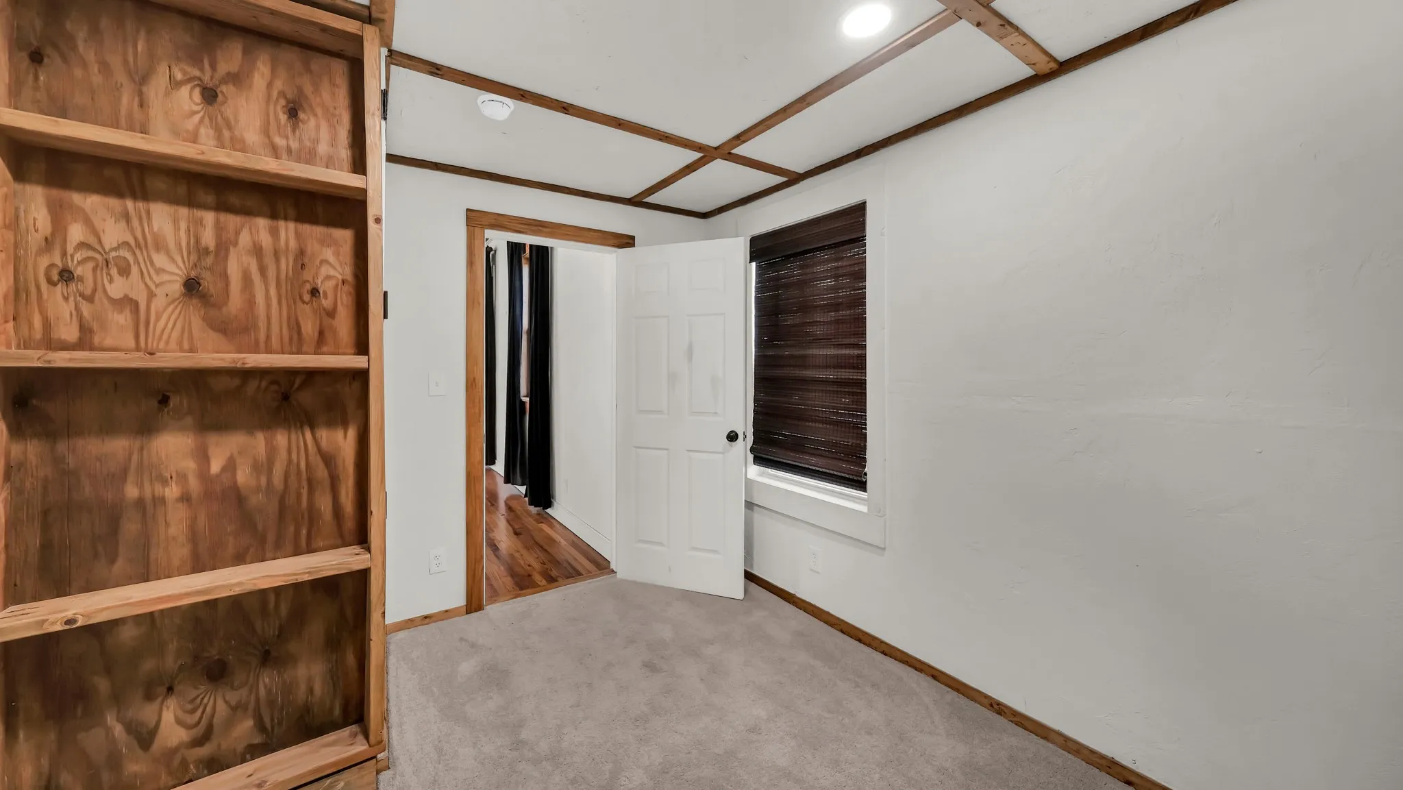 Built-in wooden shelving, wood-finish ceiling trim, recessed lighting, and carpet flooring