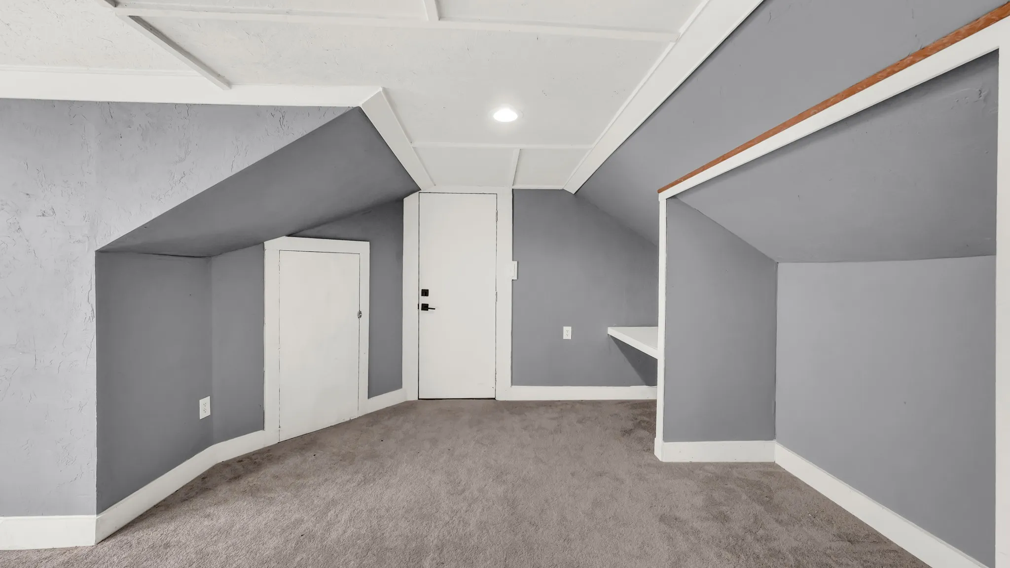 Carpeted room featuring sloped ceilings, multiple access doors, a built-in shelving unit, and recessed lighting