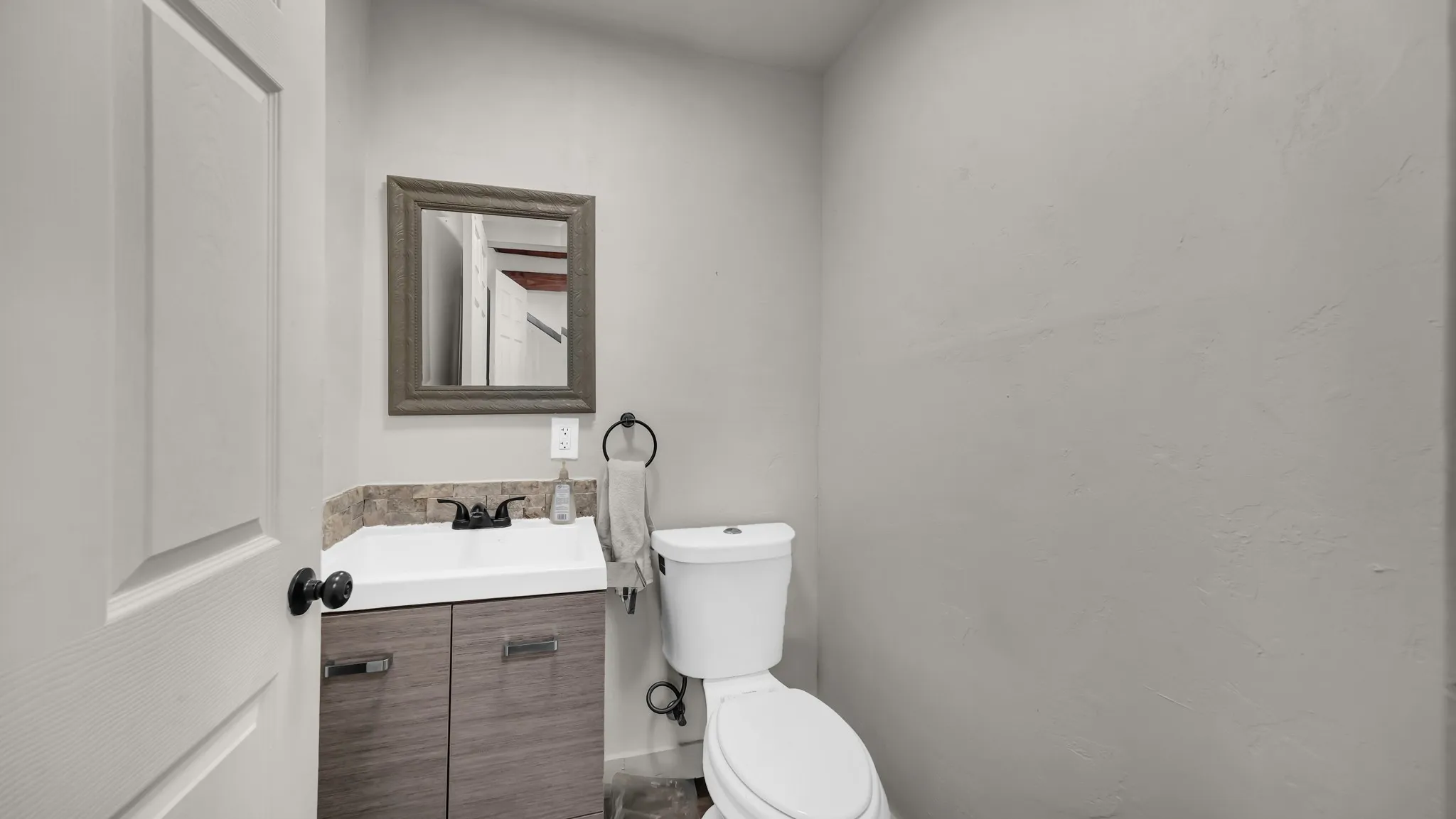 Vanity with integrated sink, wood-finish cabinetry, and dark countertop