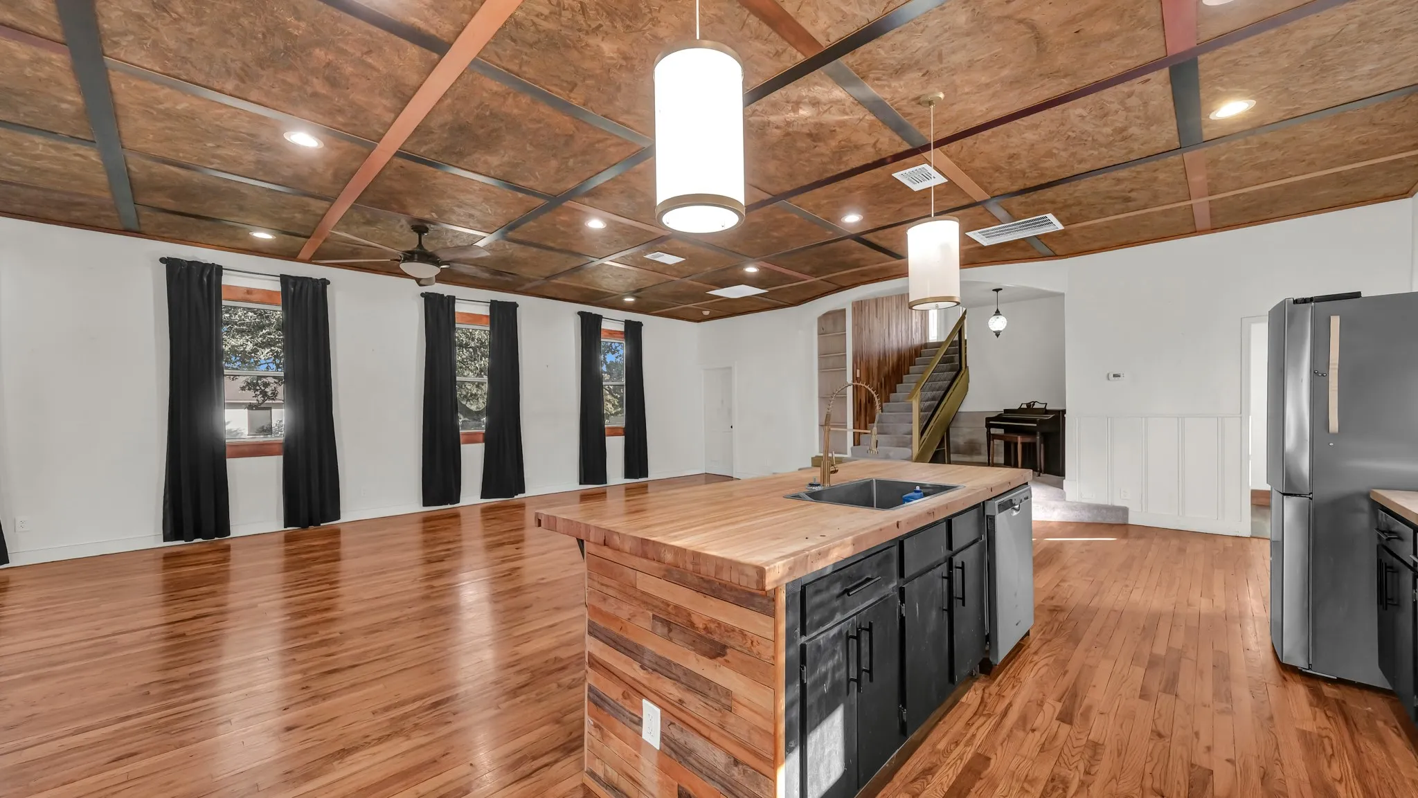 Hardwood flooring, wood-paneled ceiling with recessed lighting, kitchen island with wood countertop, built-in sink, and stainless steel dishwasher