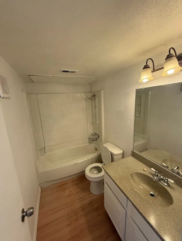 Bathroom featuring a white vanity with a stone-finish countertop, an integrated sink with a chrome faucet, and a wall-mounted mirror