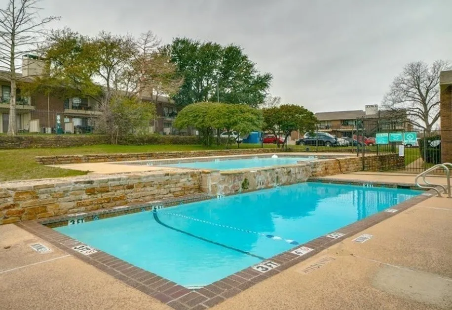 Dual outdoor swimming pools with surrounding stone accents and concrete decking