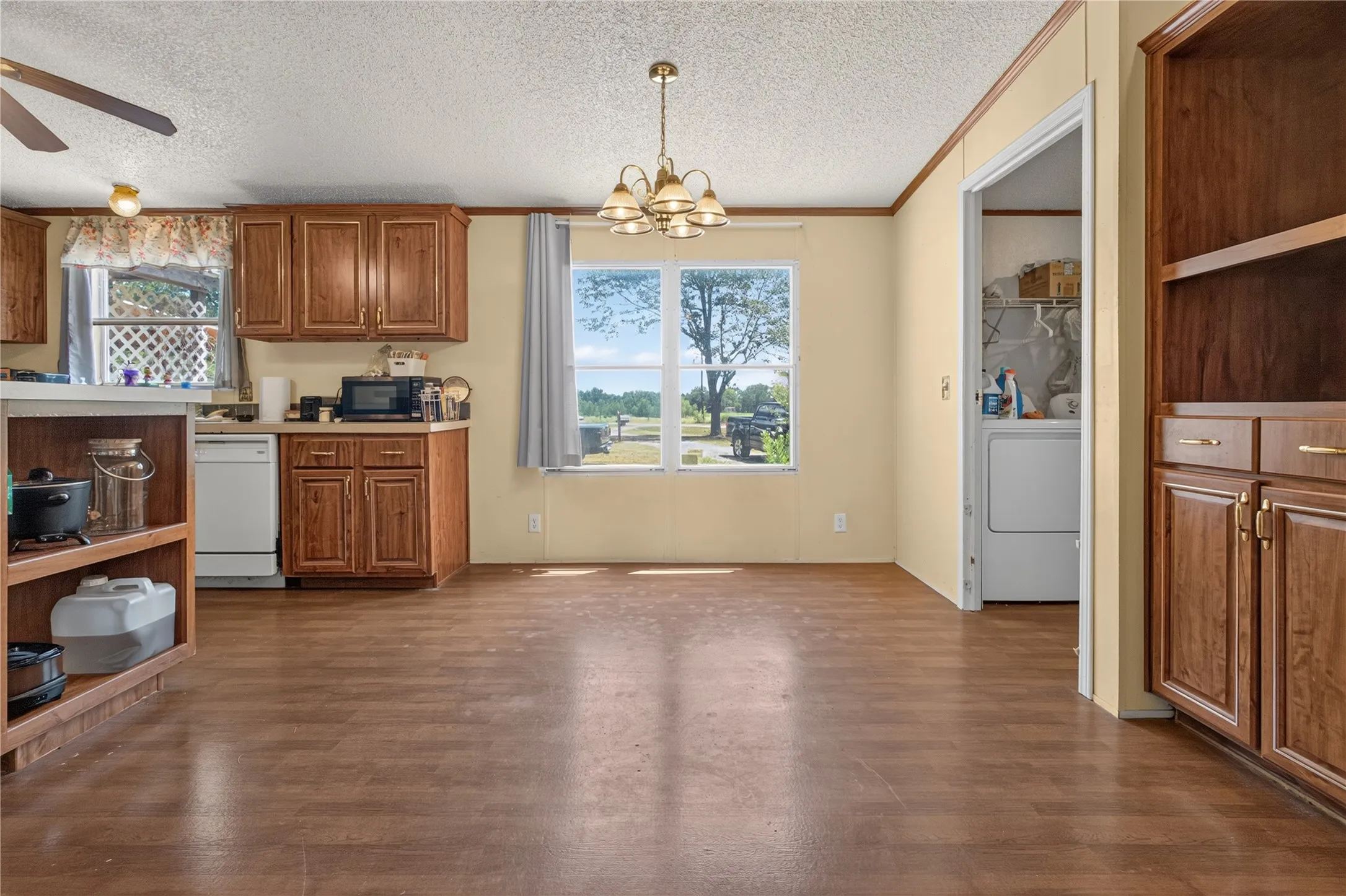 Spacious open-concept living area showcasing wood-finish flooring throughout, warm cream-colored walls, and abundant natural light from large windows