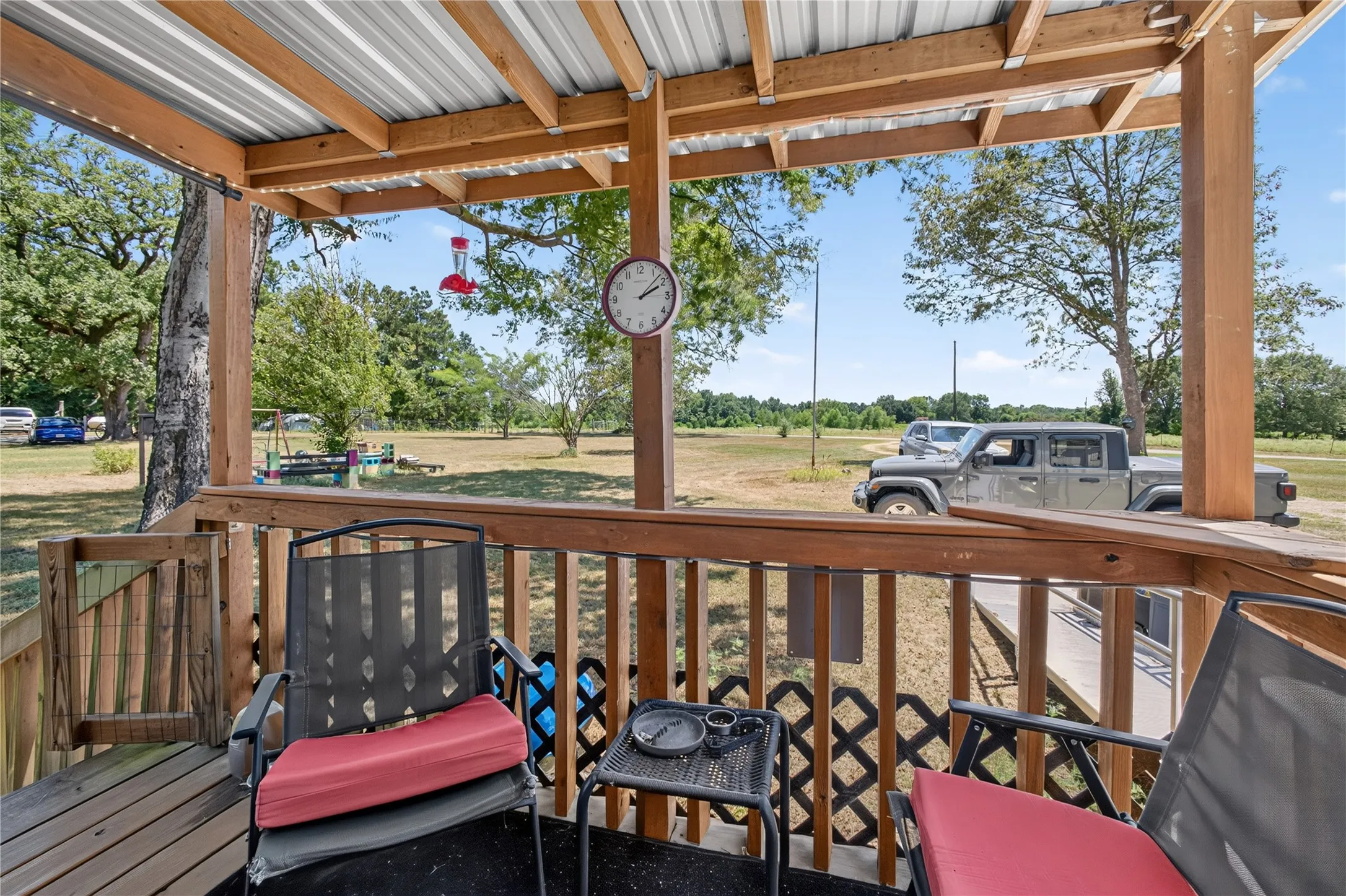 Covered porch featuring a metal roof, wood support beams, and a wood railing