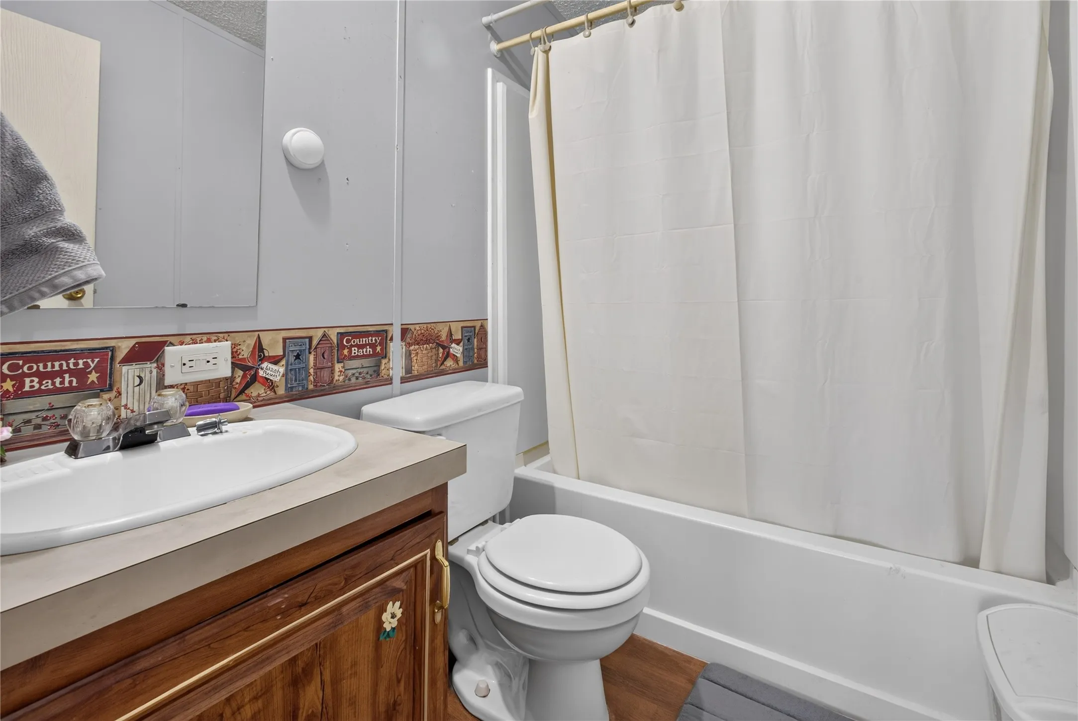 Bathroom featuring a white bathtub, toilet, and vanity with a single basin sink