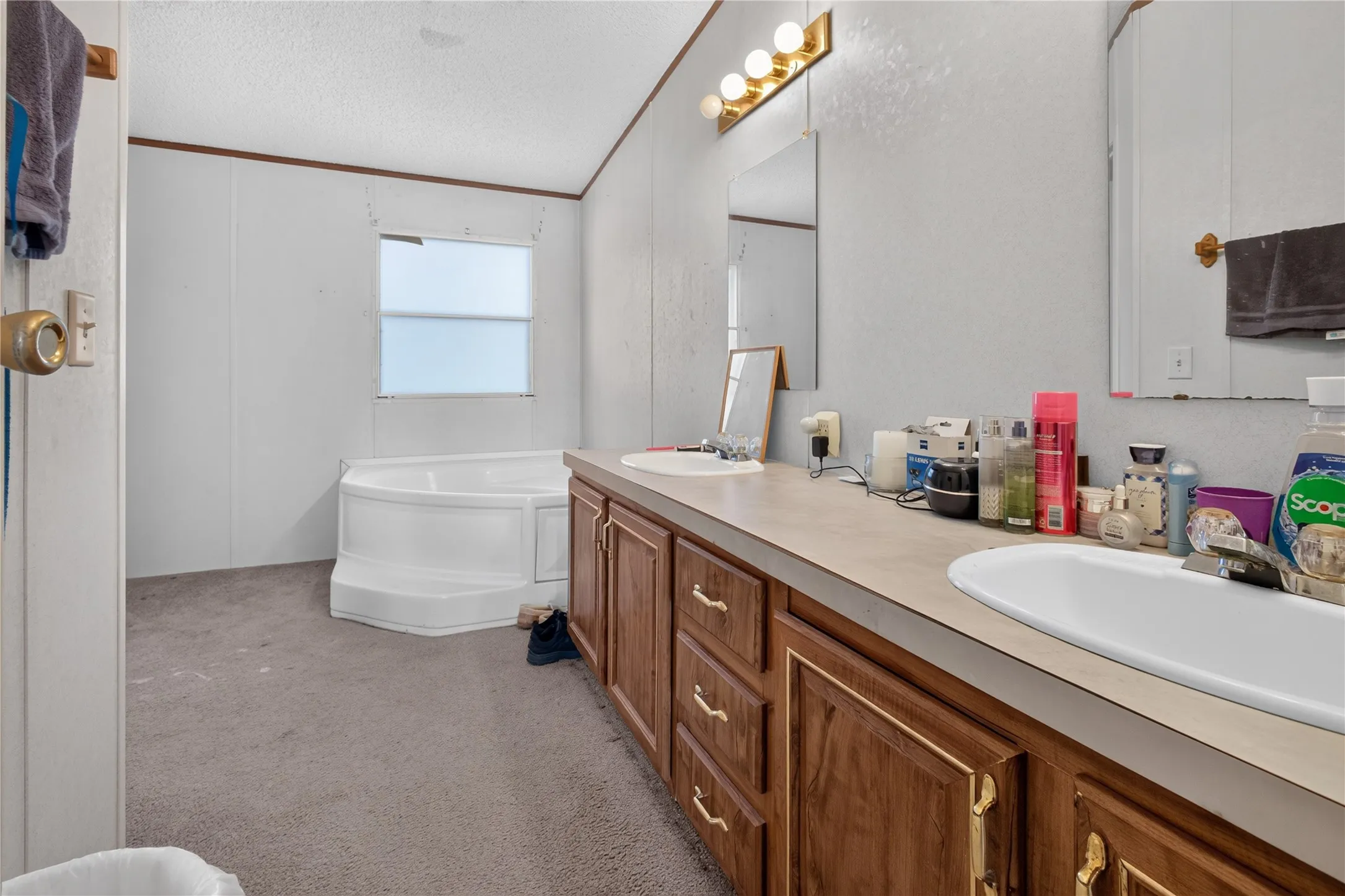 Double vanity with integrated sinks, wood-finish cabinetry, and overhead lighting